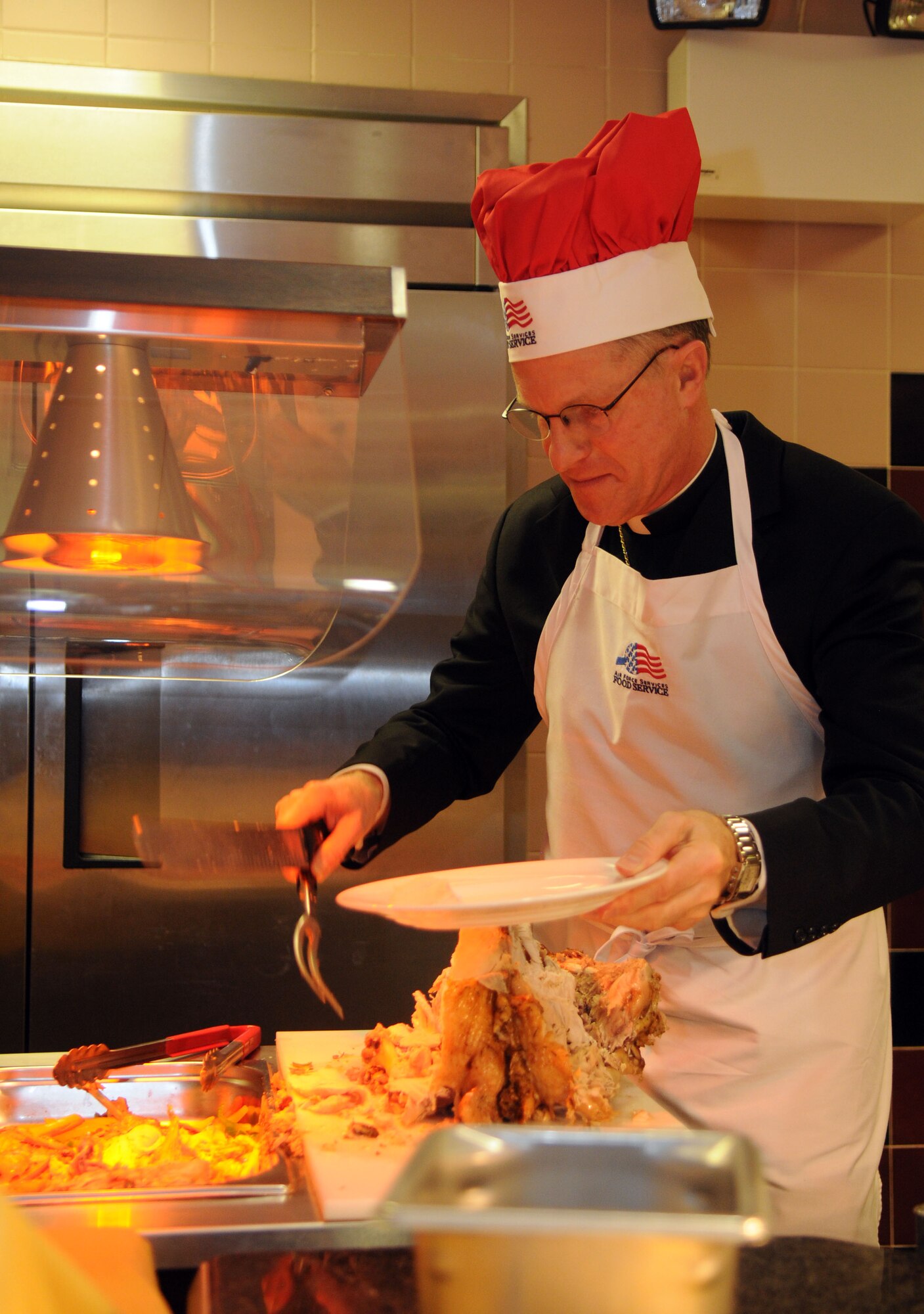 Archbishop Timothy Broglio, U.S. Archdiocese for the Military Services, carves turkey during the Thanksgiving lunch served in celebration of the American holiday Nov. 22, 2012, at the Gateway Dining Facility at RAF Mildenhall, England. Several distinguished visitors joined the staff of the dining facility to serve lunch to around 350 members of Team Mildenhall. (U.S. Air Force photo by Staff Sgt. Austin M. May/Released)