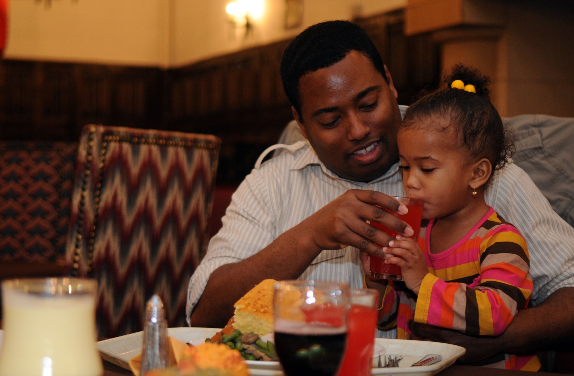 Tech. Sgt. Edwin Bispat, 100th Communications Squadron Unit Training Manager, shares a glass of juice with his daughter Alana, 2, during theThanksgiving lunch Nov. 22, 2012, at the Gateway Dining Facility, RAF Mildenhall, England. The 100th Force Support Squadron prepared the feast to allow American service members and their families stationed in England to enjoy the holiday. (U.S. Air Force photo by Staff Sgt. Austin M. May/Released)