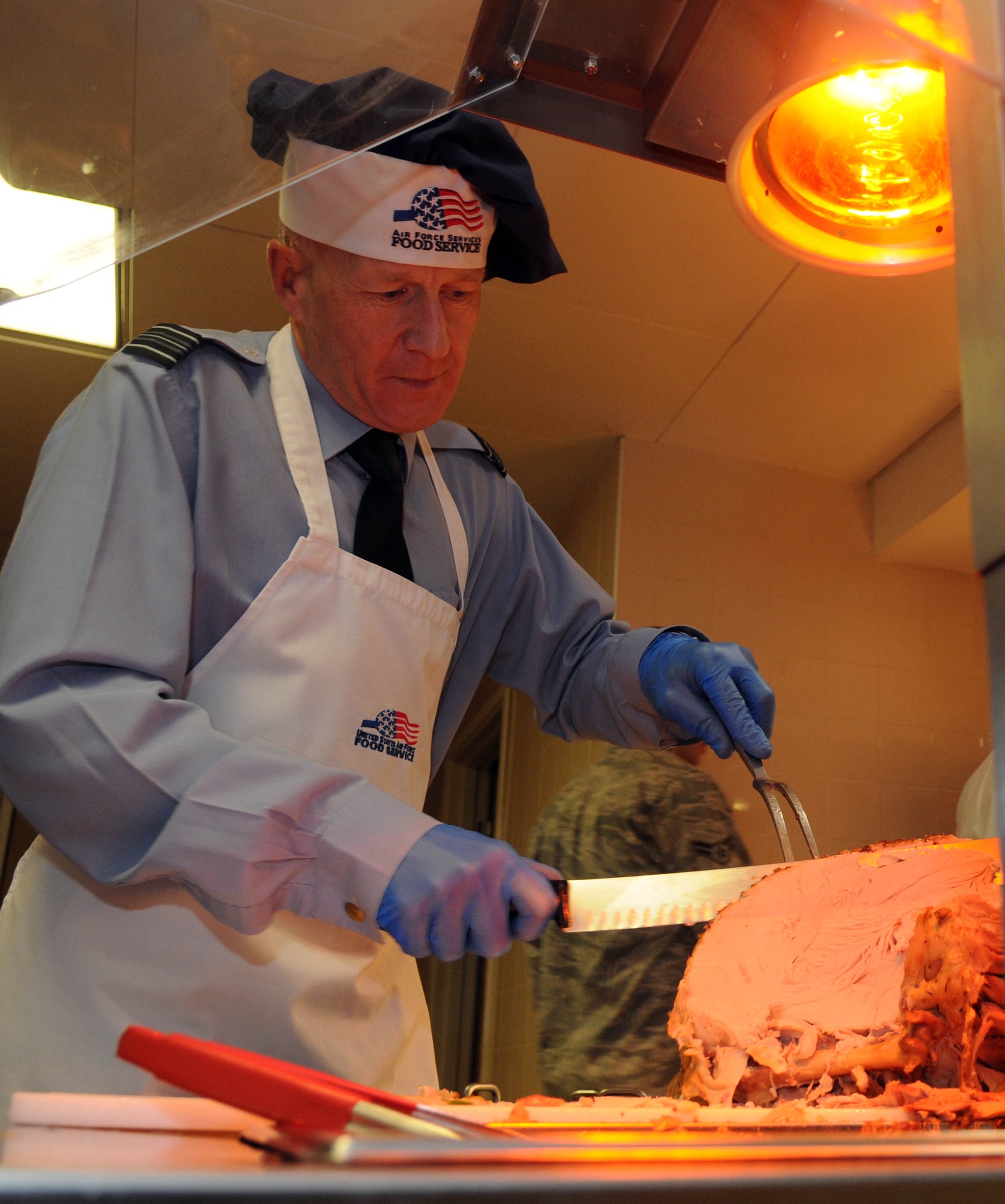Sq. Ldr. Rick Fryer, RAF station commander, carves turkey during the Thanksgiving lunch served in celebration of the American holiday Nov. 22, 2012, at the Gateway Dining Facility at RAF Mildenhall, England. Several distinguished visitors joined the staff of the dining facility to serve lunch to around 350 members of Team Mildenhall. (U.S. Air Force photo by Staff Sgt. Austin M. May/Released)