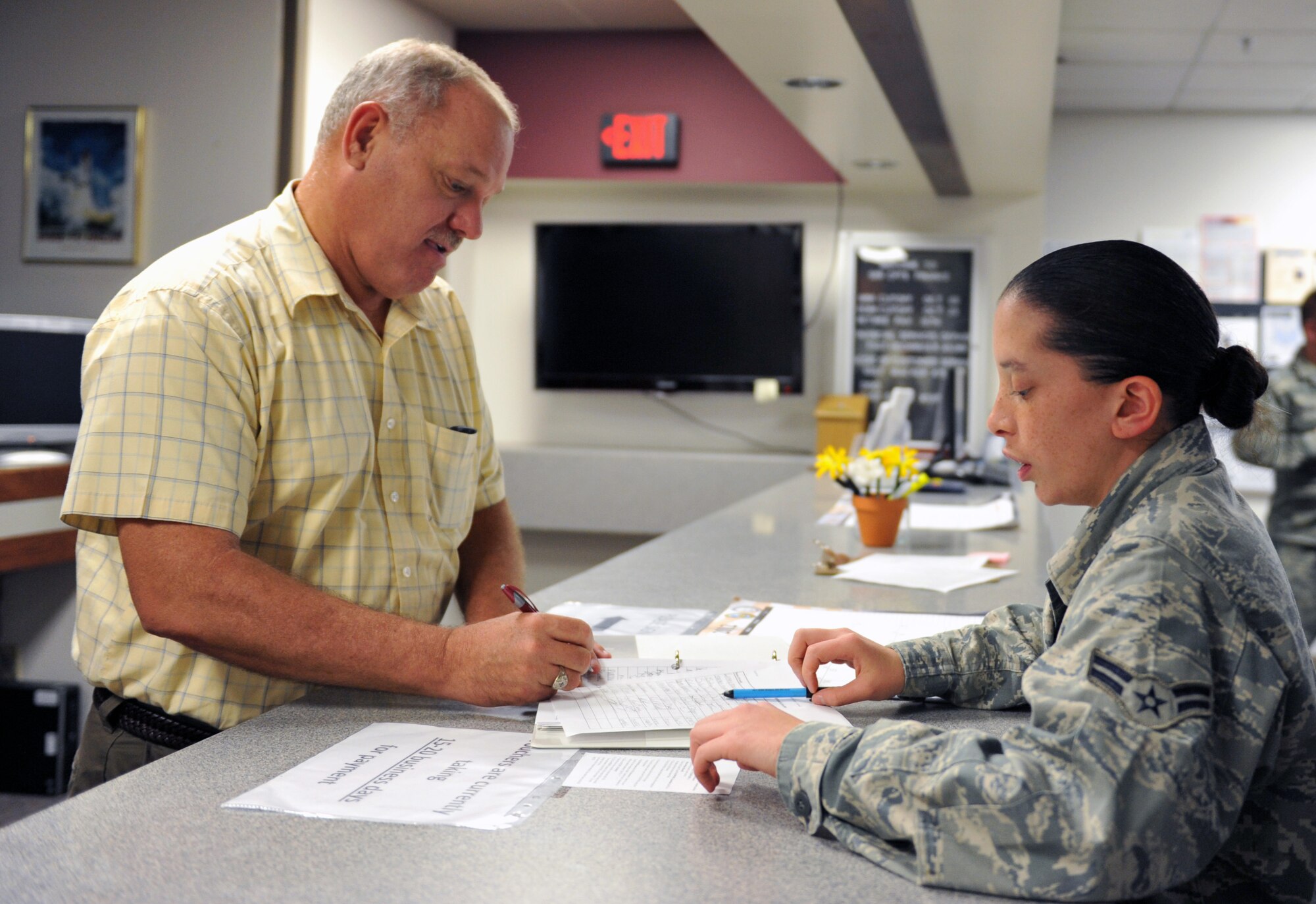 WHITEMAN AIR FORCE BASE, Mo. -- Airman 1st Class Melissa Malcolm, 509th Comptroller Squadron customer service representative, assists a customer with a travel voucher form. The 509th CPTS Financial Services Office provides a broad-based financial service to all service members and civilians, one of which is travel pay assistance. (U.S. Air Force photo/Heidi Hunt) (Released)