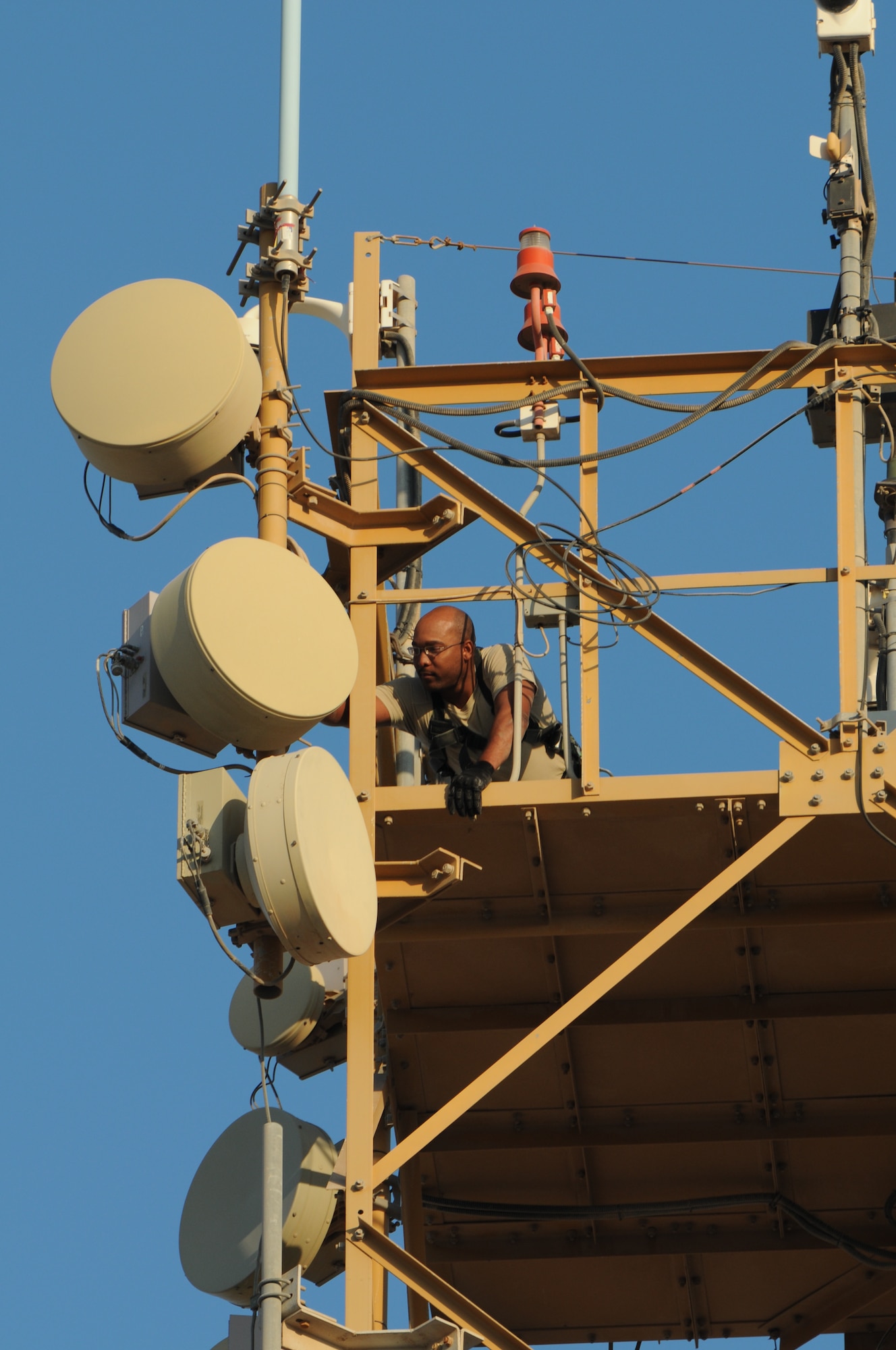 Staff Sgt. Lawrence Standifer, 379th Expeditionary Security Forces Squadron tactical automated security system noncommissioned officer in charge, repairs a microwave antenna at the top of a 140-foot equipment tower Nov. 21, 2012. TASS is an intrusion detection and surveillance system used for security monitoring around fixed site airbases. The system consists of thermal imagers, sensors, communications, power and annunciation components, which provides intrusion detection, assessment and surveillance. Sandifer is responsible for day-to-day system maintenance, inventory and training on the system. He is a native of Fayetteville, N.C. and is deployed from Hollmon Air Force Base, N.M. (U.S. Air Force photo/Senior Airman Bryan Swink)