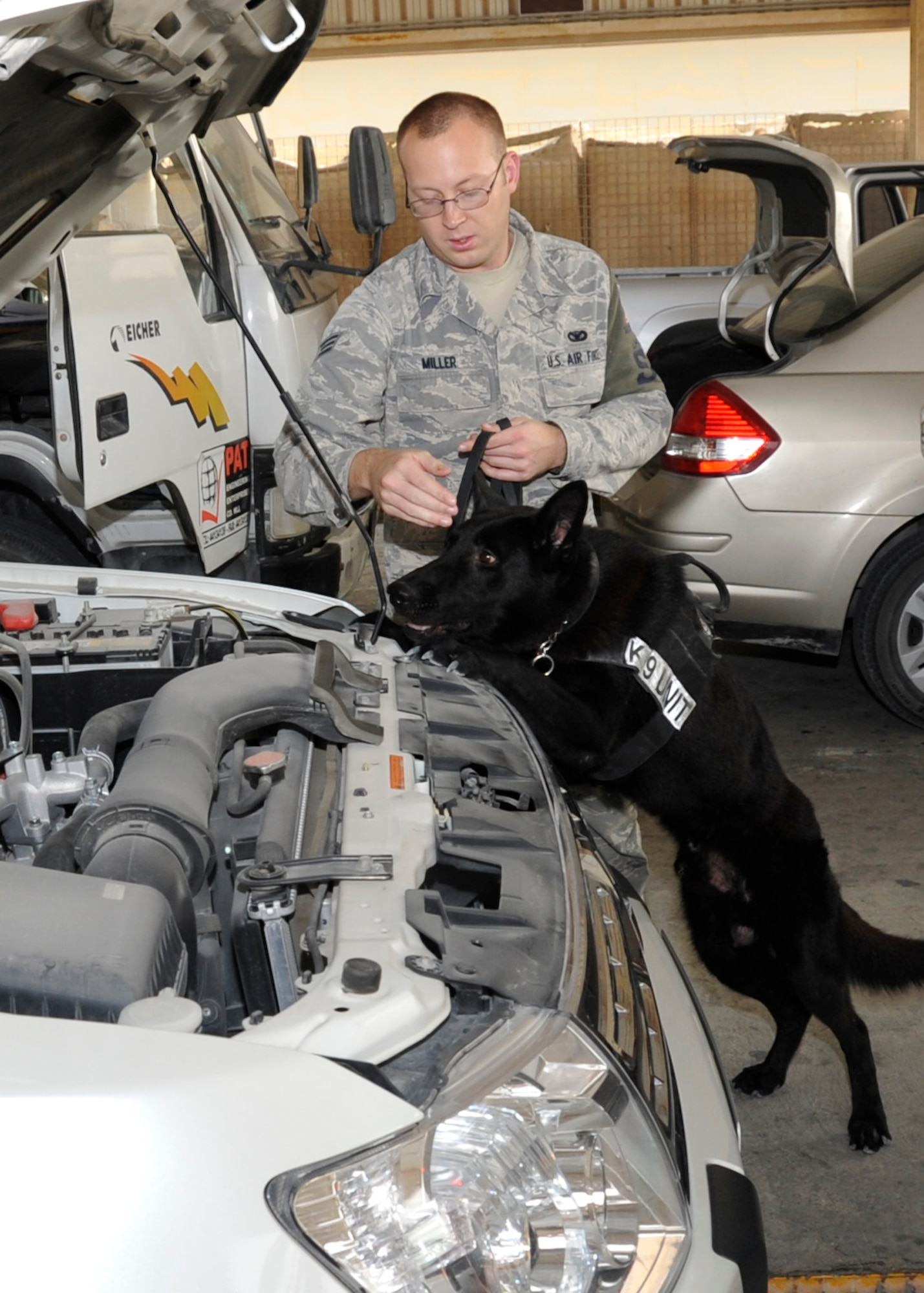 Senior Airman James Miller, 379th Expeditionary Security Force Squadron K-9 handler, conducts a routine vehicle inspection with his military working dog, Demon, Nov. 20, 2012. All vehicles must be thoroughly searched before proceeding onto the installation. Demon's primary mission is to detect explosives or drugs that may be hidden in the vehicles. The 379th ESFS K-9 unit conducts more than 600 vehicle inspections a day. Miller, a native of Fayetteville, N.C., is deployed from Travis Air Force Base, Calif. (U.S. Air Force photo/Senior Airman Bryan Swink)