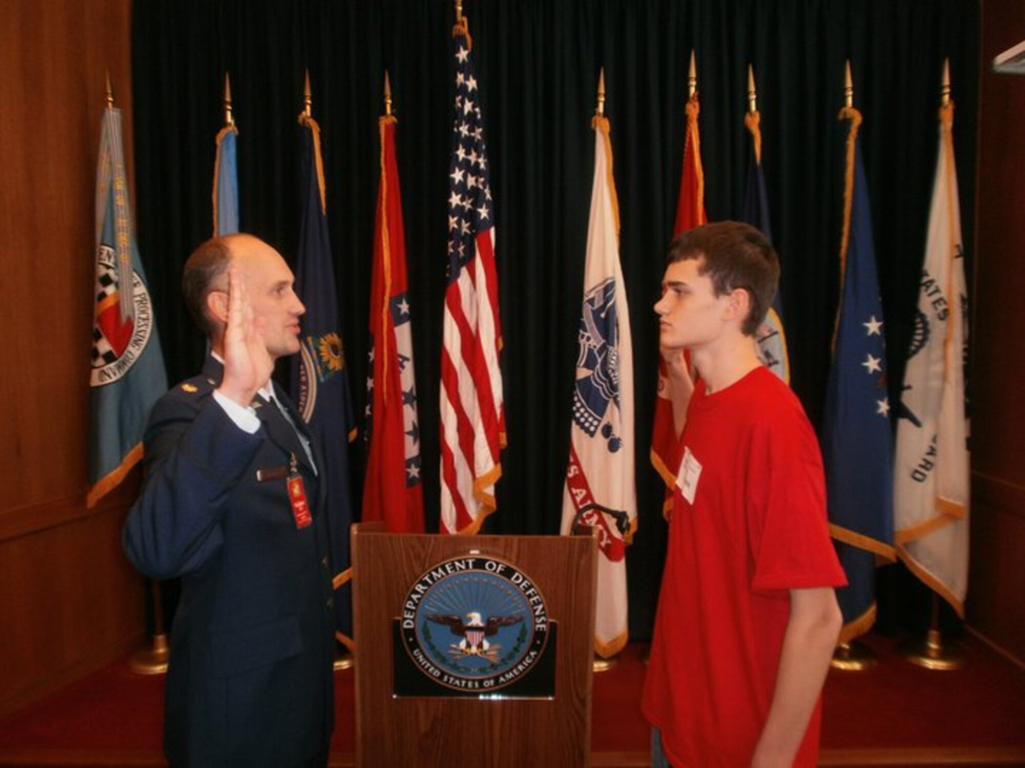 (Left) Air Force Maj. Christopher Gering swears in his son, Marshal, at a Military Entrance Processing Station before Marshal enlists with the U.S. Army. Currently, Maj. Gering provides battle management and command and control over the skies of Afghanistan while Marshal conducts route clearance in and around the Kandahar Province and Panjwey District. Both are currently deployed in support of Operation Enduring Freedom. (Courtesy photo)