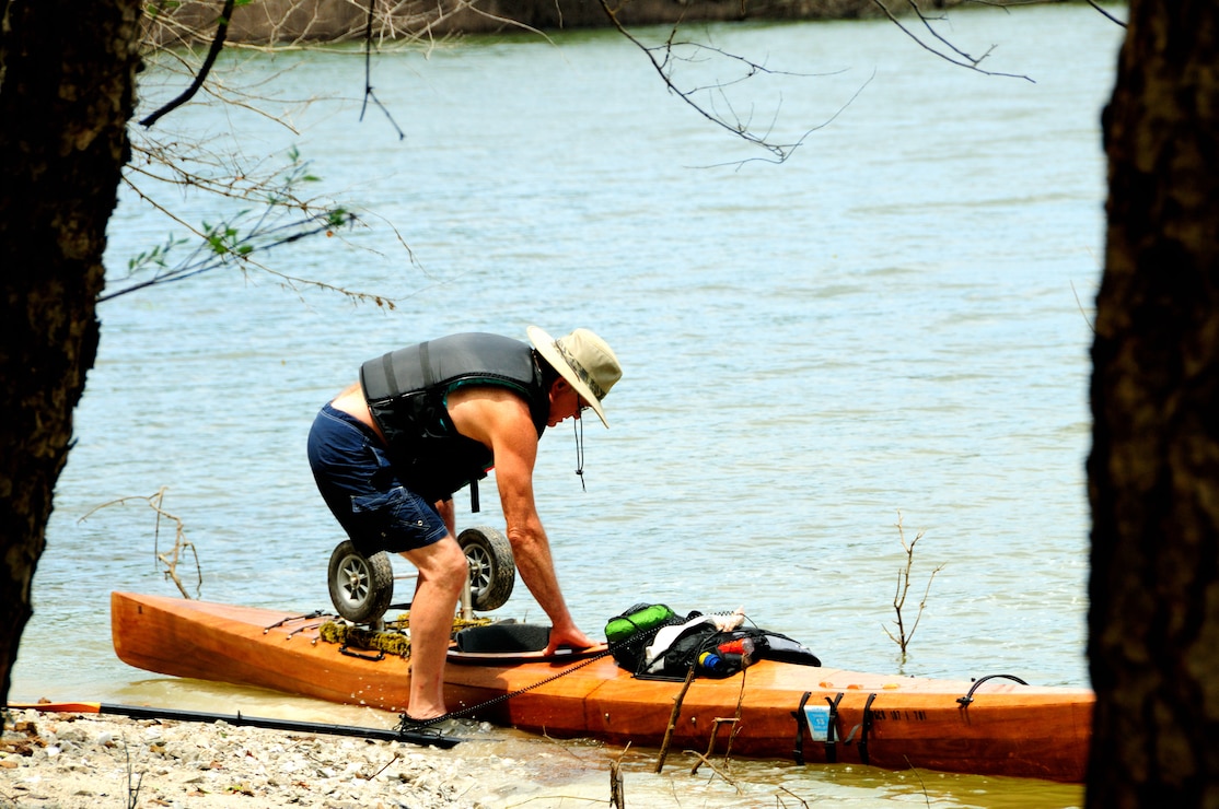 Paddler along shore with kayaks