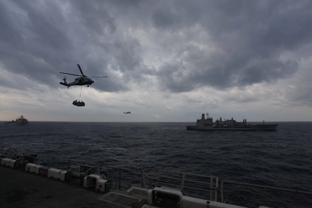 USNS John Lenthall holds a position near USS New York (back left) and USS Iwo Jima while an MH-60S Knight Hawk helicopter transports food and supplies to USS Iwo Jima during a replenishment at sea detail, or RAS, Nov. 24, 2012. During the resupply USS Iwo Jima took on fuel, fresh fruits and vegetables, dry goods, and supplies to sustain the ship and crew while at sea. The 24th Marine Expeditionary Unit is deployed with the Iwo Jima Amphibious Ready Group in the 6th Fleet area of responsibility serving as an expeditionary crisis response force capable of a variety of missions, from full scale combat to evacuations and humanitarian assistance. Since deploying in March, they have supported a variety of missions in the U.S. Central, Africa and European Commands, assisted the Navy in safeguarding sea lanes, and conducted various bilateral and unilateral training events in several countries in the Middle East and Africa. (U.S. Marine Corps photo by Lance Cpl. Tucker S. Wolf/Released) 