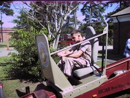A Marine rides the "Convincer" -- an apparatus designed to demonstrate the importance of wearing a seat belt while riding in a vehicle.