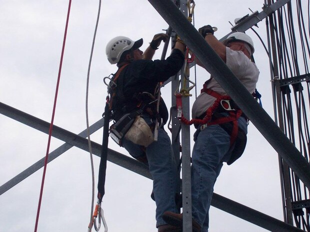 Two Safety Specialists from Safety Department demonstrate an aerial rescue during a simulated fall from a communication tower; notice the fall protection harness and related equipment donned by both.