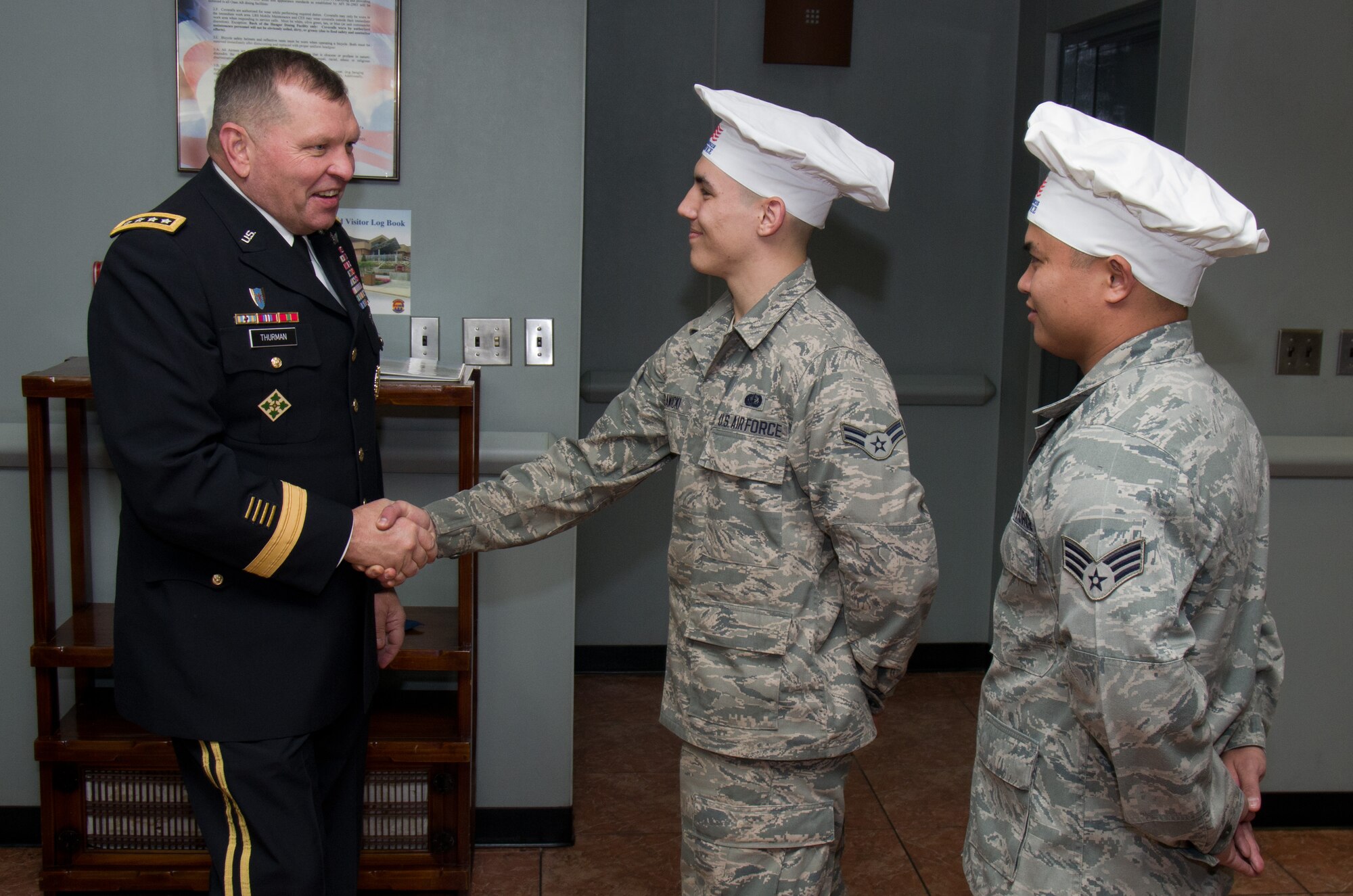 Gen. James Thurman, U.S. Forces Korea commander, greets Airman 1st Class Brent Sawicki and Senior Airman Danryll Tanggol-Mendoza, 51st Force Support Squadron Ginko Tree dining facility shift workers, during a Thanksgiving day celebration, Nov. 22, 2012. Thurman and other base leaders served food to Osan Airmen and families for the Thanksgiving feast. (U.S. Army photo/Sgt. Brian Gibbons)