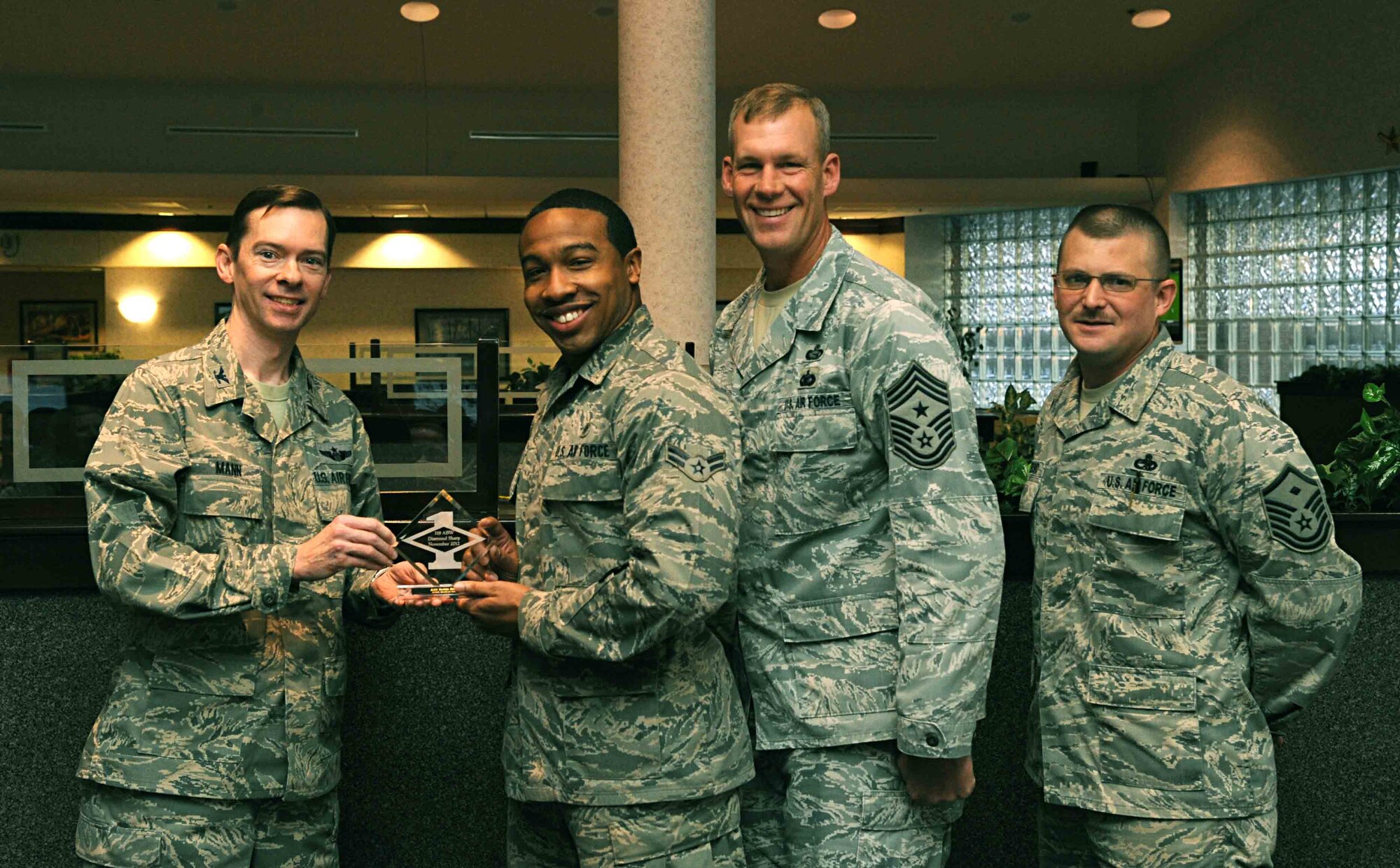 Col. Christopher Mann, 319th Air Base Wing vice commander, presents Airman 1st Class Robin Reese, 319th Medical Operations Squadron, with a Diamond Sharp Award Nov. 15, 2012, at Airey Dining Facility on Grand Forks Air Force Base, N.D., accompanied by 319th ABW Command Chief Master Sgt. David Carlson and Master Sgt. Brian Dipersio, 319th Medical Group first sergeant. The Diamond Sharp Award is given to Airmen who epitomize service before self and strive for excellence at work and off duty. (U.S. Air Force photo/Senior Airman Amber Bennett)
