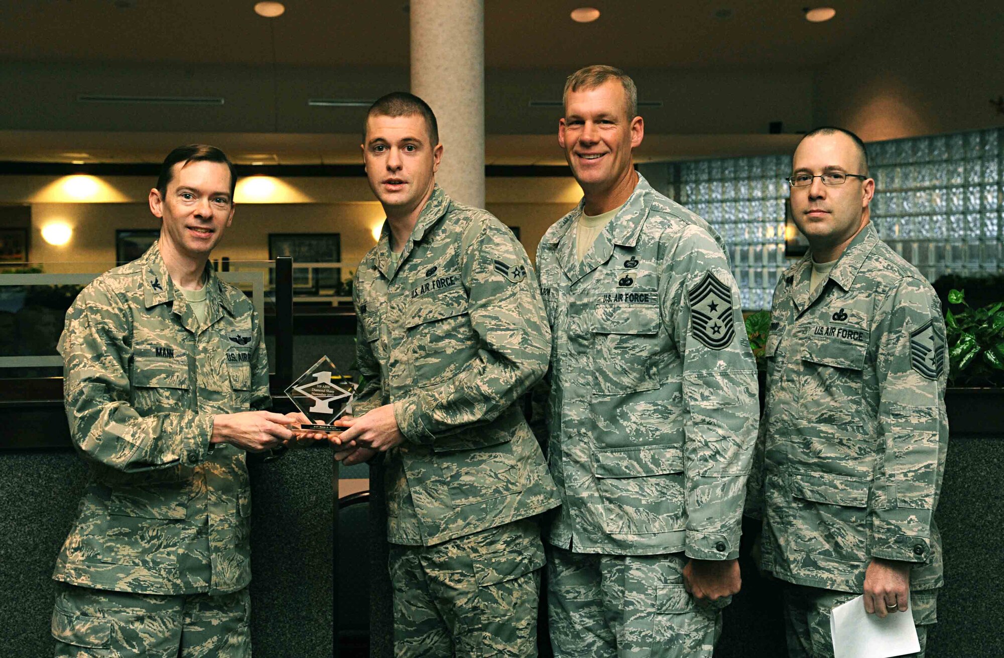 Col. Christopher Mann, 319th Air Base Wing vice commander, presents Airman 1st Class Ryan Kuhn, 319th Communications Squadron, with a Diamond Sharp Award Nov. 15, 2012, at Airey Dining Facility on Grand Forks Air Force Base, N.D., accompanied by 319th ABW Command Chief Master Sgt. David Carlson and Master Sgt. Jay Atwood, 319th CS first sergeant. The Diamond Sharp Award is given to Airmen who epitomize service before self and strive for excellence at work and off duty. (U.S. Air Force photo/Senior Airman Amber Bennett)