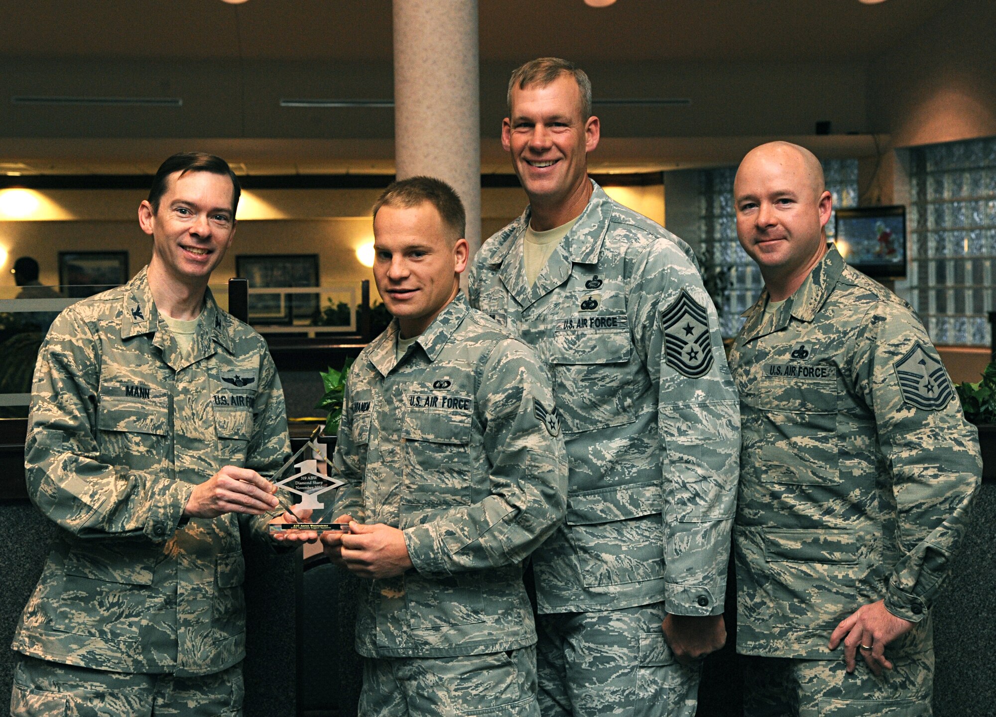 Col. Christopher Mann, 319th Air Base Wing vice commander, presents Senior Airman Aaron Waaraniemi, 319th Operations Support Squadron, with a Diamond Sharp Award Nov. 15, 2012, at Airey Dining Facility on Grand Forks Air Force Base, N.D., accompanied by 319th ABW Command Chief Master Sgt. David Carlson and Master Sgt. Richie McCorkle, 319th OSS first sergeant. The Diamond Sharp Award is given to Airmen who epitomize service before self and strive for excellence at work and off duty. (U.S. Air Force photo/Senior Airman Amber Bennett)