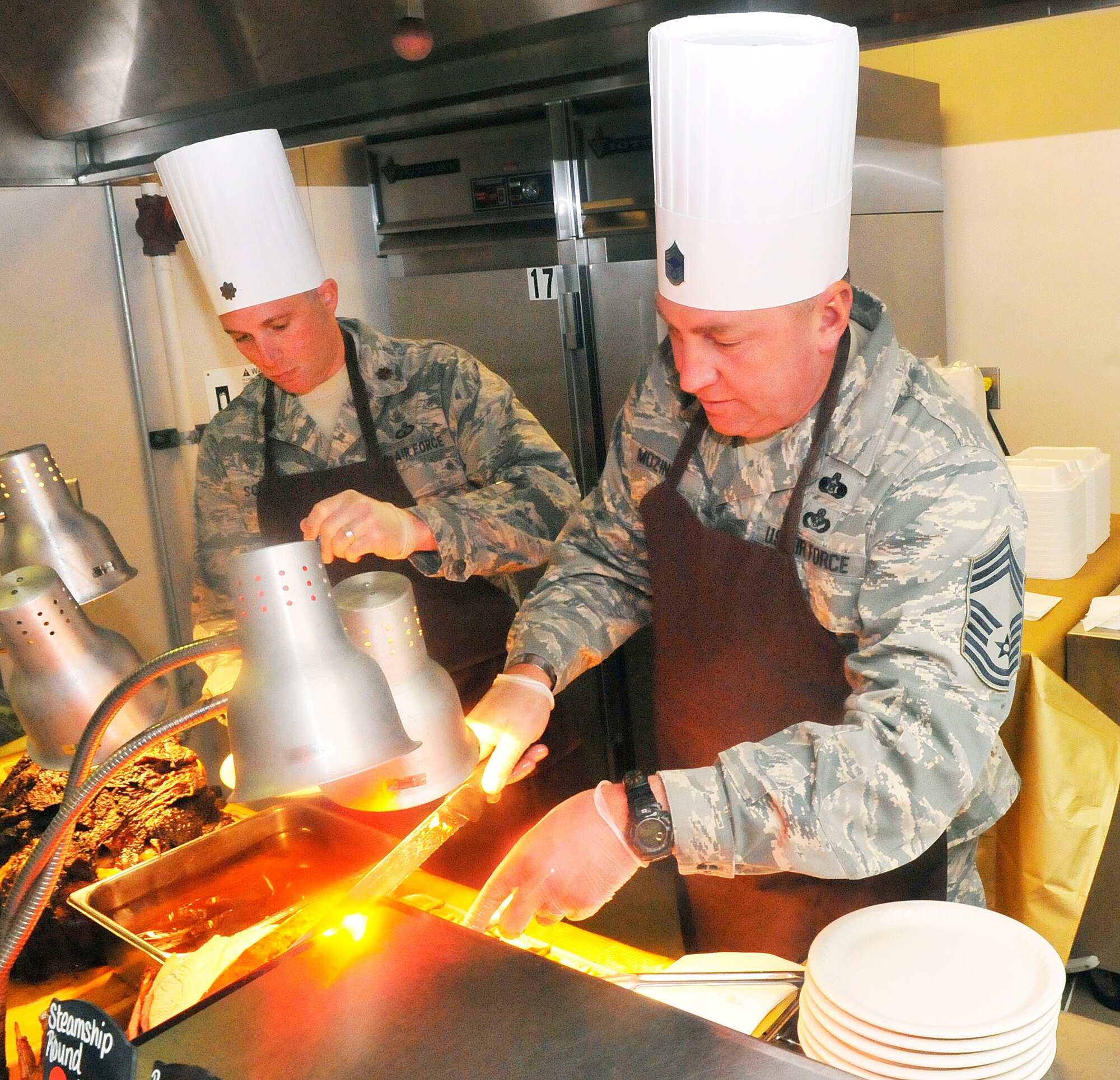 L-R, Maj. R. E. Schmidt, 51st Combat Communications Squadron commander, and Chief Master Sgt. Christopher Mozingo, Air Force Reserve Command/A7XEM, carve meats for the Thanksgiving dinner at Wynn Dining facility.  (U. S. Air Force photo/Sue Sapp)