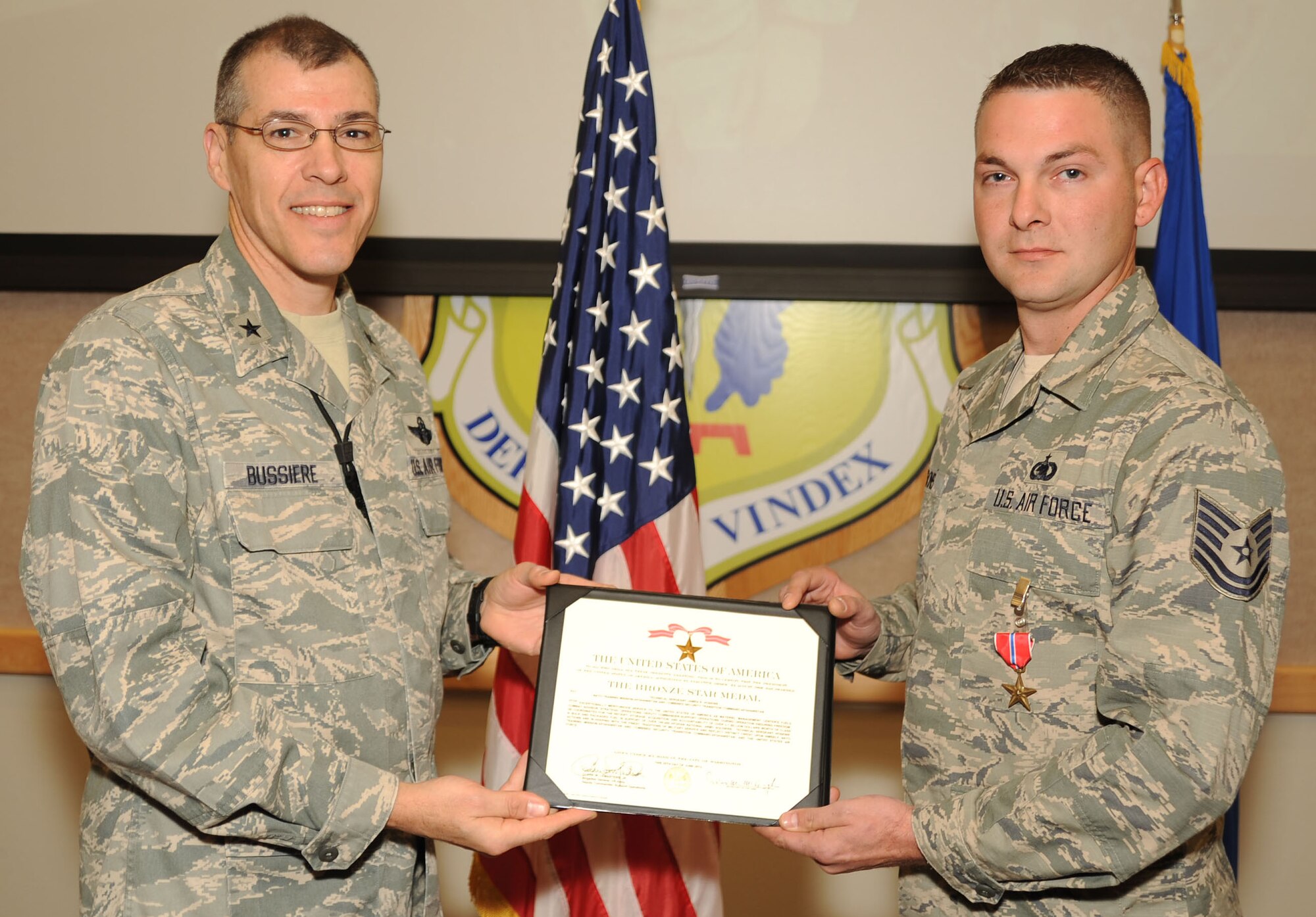 Brig. Gen. Thomas Bussiere, 509th Bomb Wing commander, presents the Bronze Star to Tech. Sgt. James Hoskins, 509th Logistics Readiness Squadron quality assurance inspector, Nov. 20 at Whiteman Air Force Base, Mo. Hoskins distinguished himself by serving on hundreds of combat patrols and assuming increased responsibilities while deployed. (U.S. Air Force photo/Senior Airman Nick Wilson) (Released)
