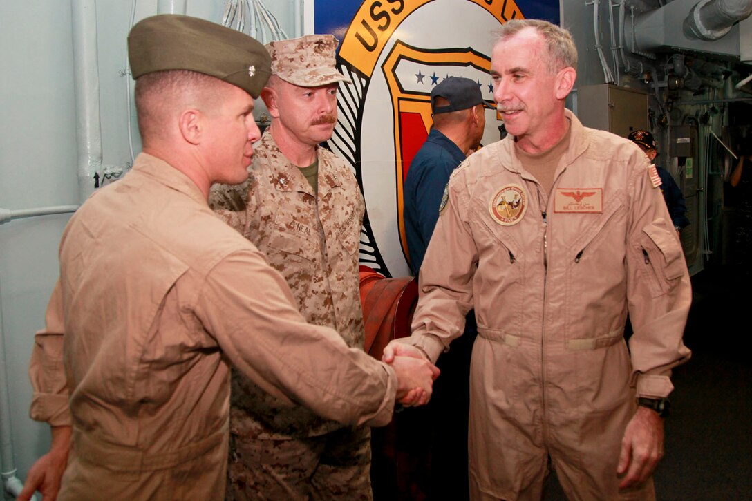 Lieutenant Col. Ned M. Biehl (left), commanding officer, Marine Medium Helicopter Squadron 364 (Rein.), and John R. O'Neal, executive officer, 15th Marine Expeditionary Unit, greet Rear Adm. William K. Lescher, commander, Expeditionary Strike Group 5, after he arrived aboard USS Peleliu, Nov. 24. The 15th MEU is deployed as part of the Peleliu Amphibious Ready Group as a U.S. Central Command theater reserve force, providing support for maritime security operations and theater security cooperation efforts in the U.S. 5th Fleet area of responsibility. (U.S. Marine Corps photo by Cpl. John Robbart III/ Released)