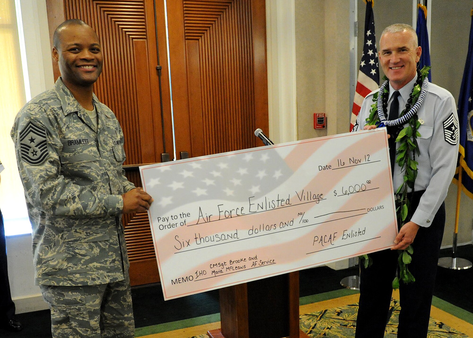 Chief Master Sgt. Leslie Bramlett, 15th Wing command chief, presents Chief Master Sgt. Brooke McLean, Pacific Air Forces command chief, with a $6,000 check for the Air Force Enlisted Village on behalf of the PACAF enlisted corps.   Mclean will be working for the Air Force Enlisted Village, which provides a safe, secure and dignified place for indigent spouses of retired Air Force personnel.  The Village’s primary goal and focus is to “Provide a Home,” and financial assistance to Air Force spouses. (U.S. Air Force photo/Tech. Sgt. Jerome S. Tayborn/Released)