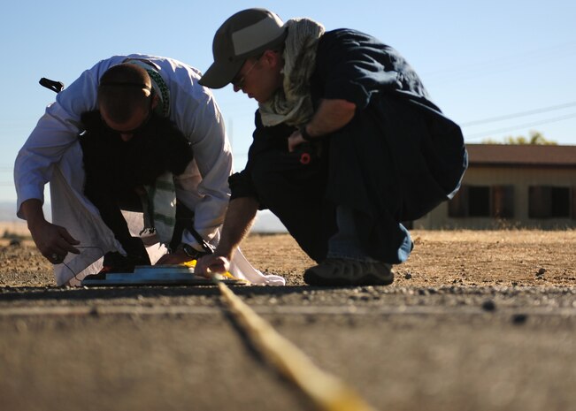 Two opposition forces simulate planting a roadside bomb during a 489th Reconnaissance Squadron training exercise at Beale Air Force Base, Calif., Oct. 17, 2012. The 489th RS is where pilots, sensor operators, and tactical system operators come to train on the MC-12W Liberty weapons system. (U.S. Air Force photo by Senior Airman Shawn Nickel/Released)