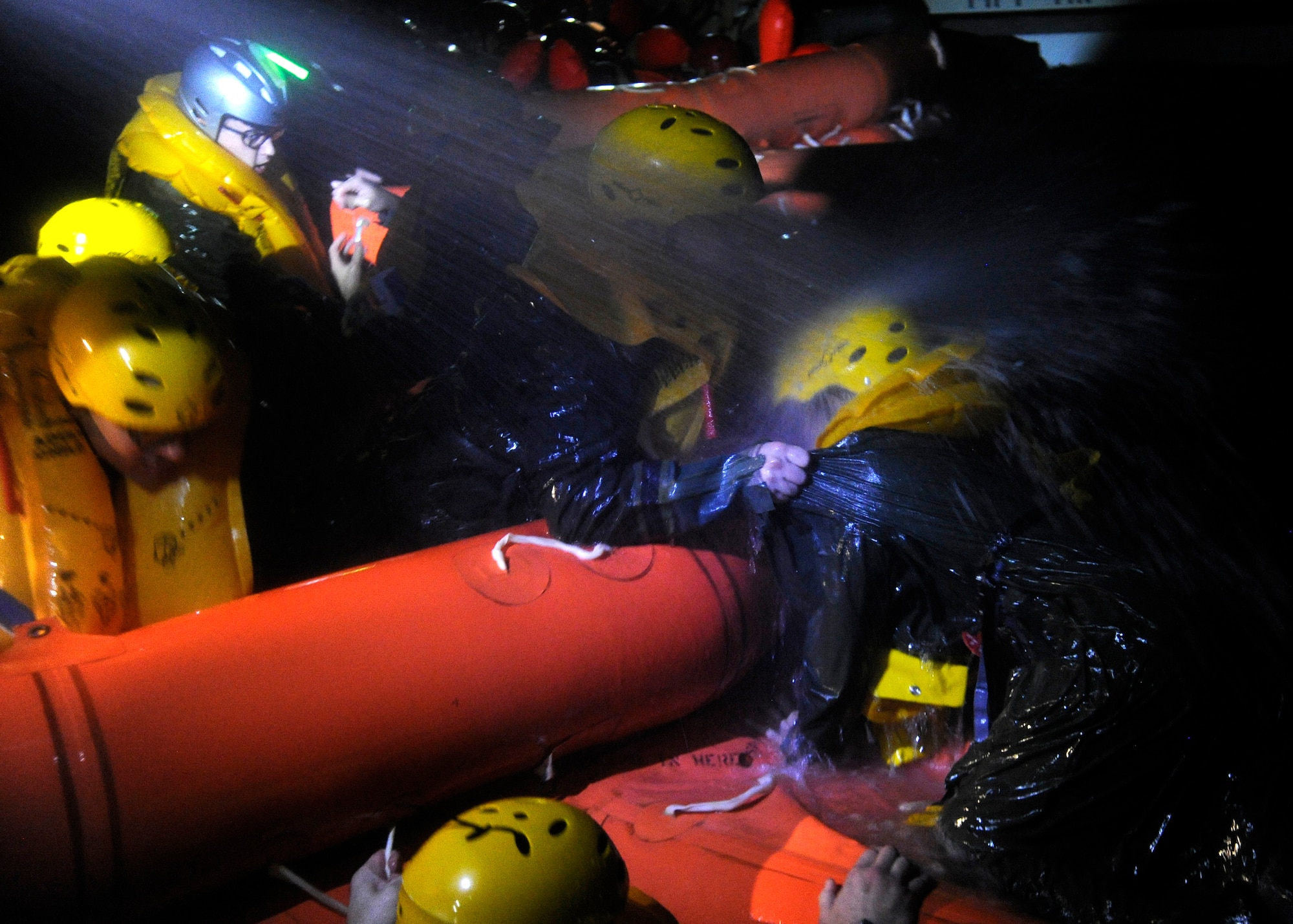 Survival, Evasion, Resistance and Escape students are hosed with water as they assist each other into the 20-man life raft at Fairchild Air Force Base, Wash., Oct. 12, 2012. The instructors simulate the extreme conditions that exist when water crashes occur. (U.S. Air Force photo by Airman 1st Class Ryan Zeski)