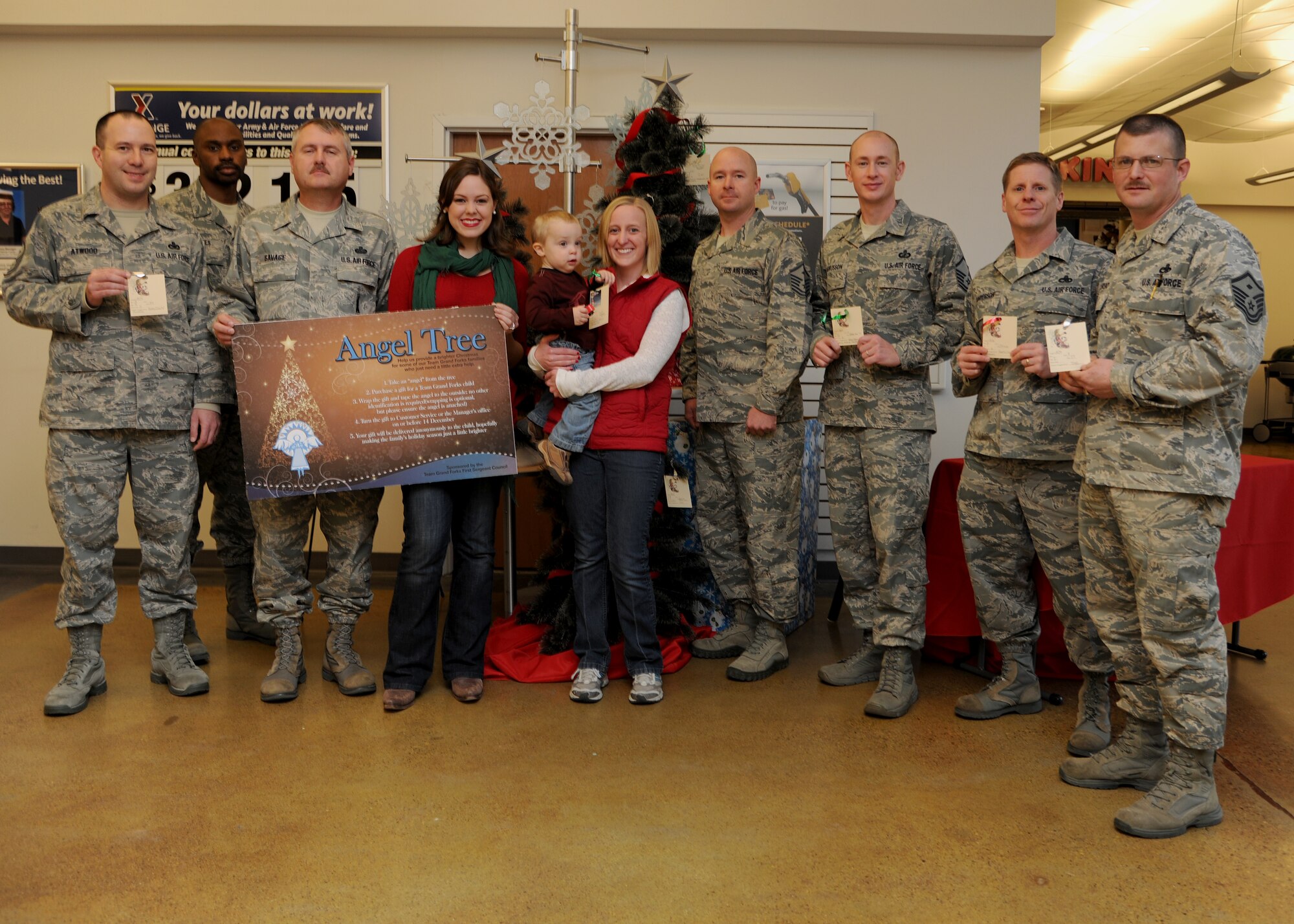 Grand Forks First Sergeant Council members present an Angel Tree with military spouses Cassie Schotanus and Bethanne Runyan on Nov. 21, 2012, at the Base Exchange on Grand Forks Air Force Base, N. D. With around 70 names provided, the purpose of the Angel Tree is to ensure every child on GFAFB has a gift to open this holiday season.  Contact your first sergeant for details or to nominate an individual or family. (U.S. Air Force photo/Airman 1st Class Ashley N. Taylor)