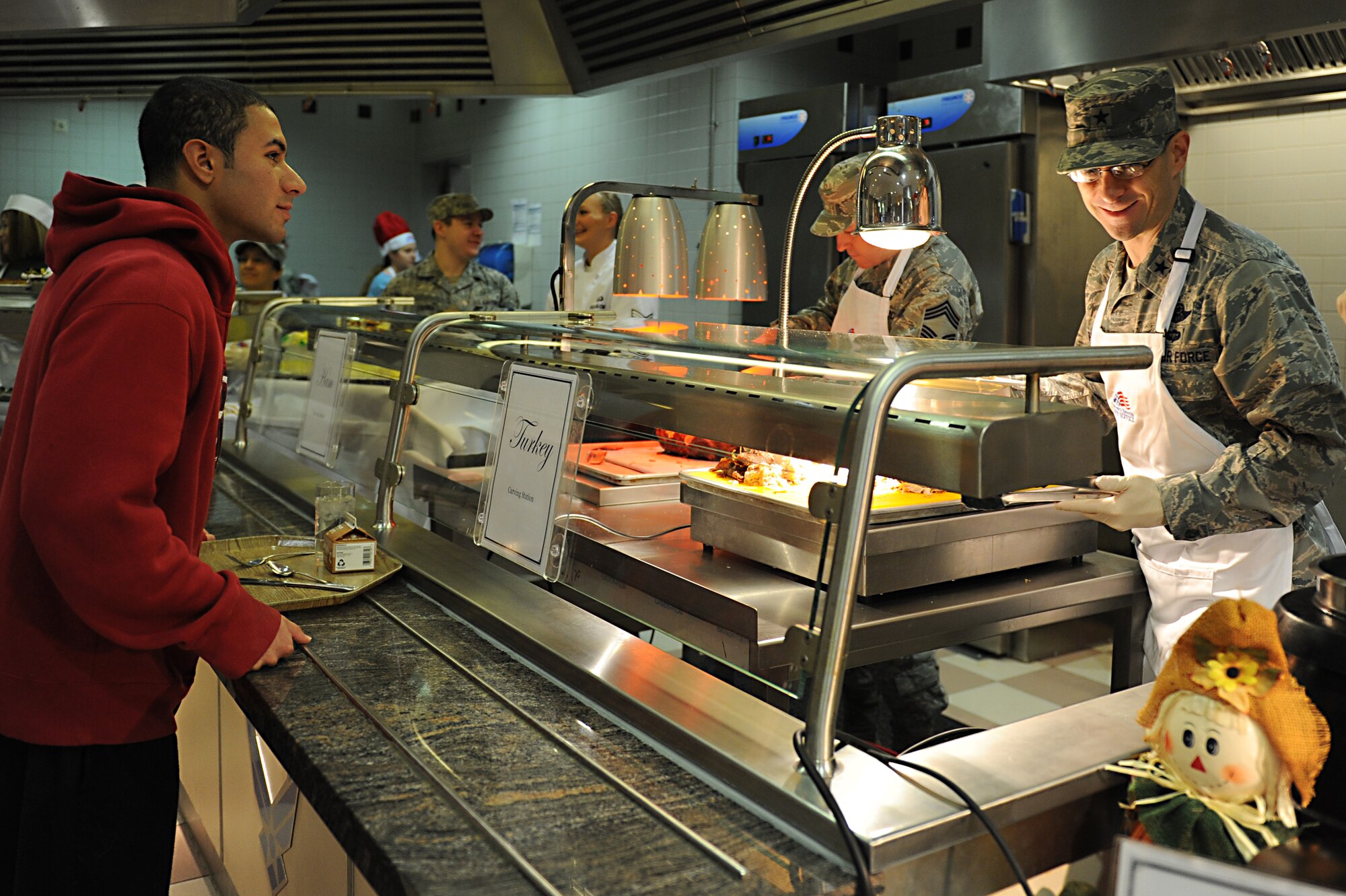 Brig. Gen. C.K. Hyde, 86th Airlift Wing commander, carves turkey for Airman 1st Class Giovanni Pinzon, 86th Munitions Squadron tactical air munitions rapid response package, on Thanksgiving Day at the Rheinland Inn Dining Facility on Ramstein Air Base, Germany, Nov. 22, 2012. The dining facility along with many base leadership volunteers and their families served up a taste of home for KMC Airmen and their families. (U.S. Air Force photo/Airmen 1st Class Holly Cook)