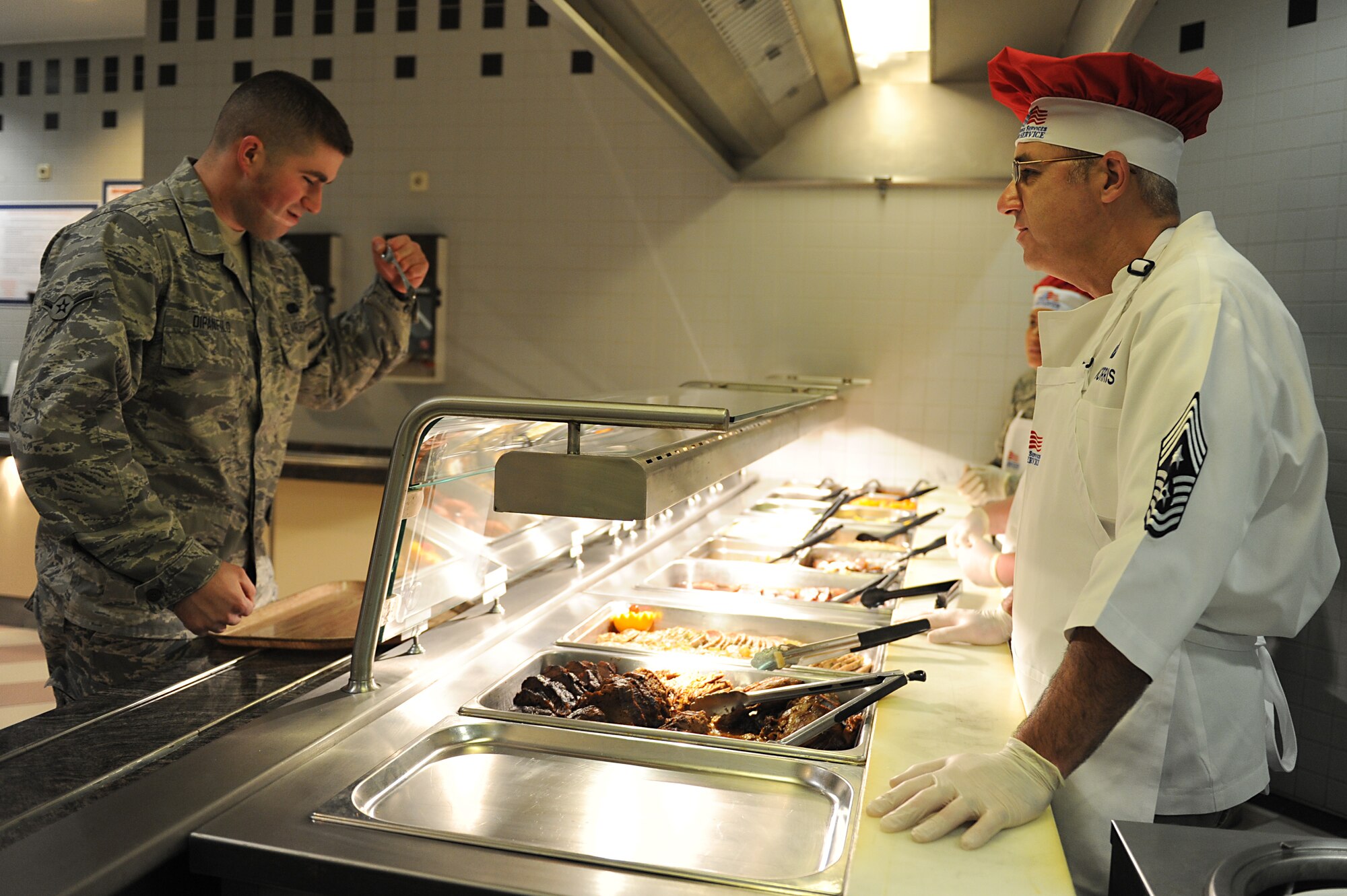 Chief Master Sgt. James Morris, 86th Airlift Wing command chief, fixes a plate of food for Airman Casey Dipanfilo, 86th Logistics Readiness Squadron fuels distribution operator, on Thanksgiving Day at the Rheinland Inn Dining Facility on Ramstein Air Base, Germany, Nov. 22, 2012. The dining facility along with many base leadership volunteers and their families served up a taste of home for KMC Airmen and their families. (U.S. Air Force photo/Airmen 1st Class Holly Cook)