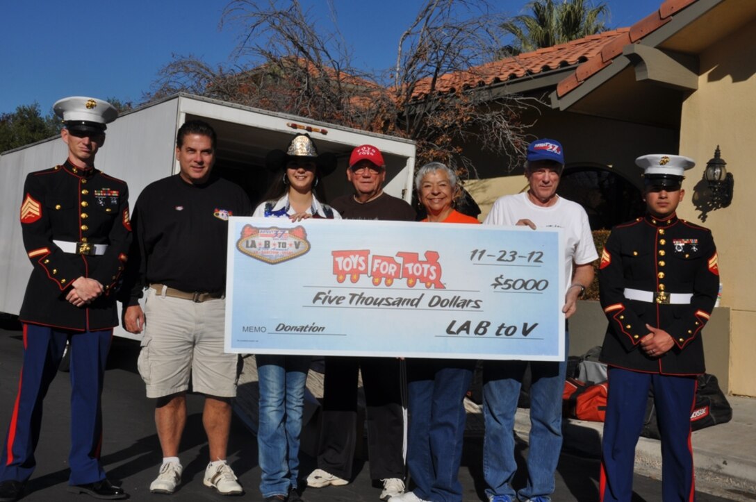 Sergeant Steven B. Waddell, a maintenance chief with Fleet Support Division aboard Marine Corps Logistics Base Barstow, Calif., Keith Huff, the event coordinator, Miranda Wessel, Barstow’s 2012 Rodeo Queen, Mal Wessel, Toys for Tots supporter and former mayor of Barstow, his wife, Connie Wessel, Paul Flanders, the D-37 Dual Sport referee, and Cpl. Miguel Verdin, an automotive diesel mechanic aboard MCLB hold the $5000 check donation to Toys for Tots received from participants of the 29th annual D-37 American Motorcycle Association’s Dual Sport ride. More than 500 riders collectively put in the money as well as numerous toy donations.