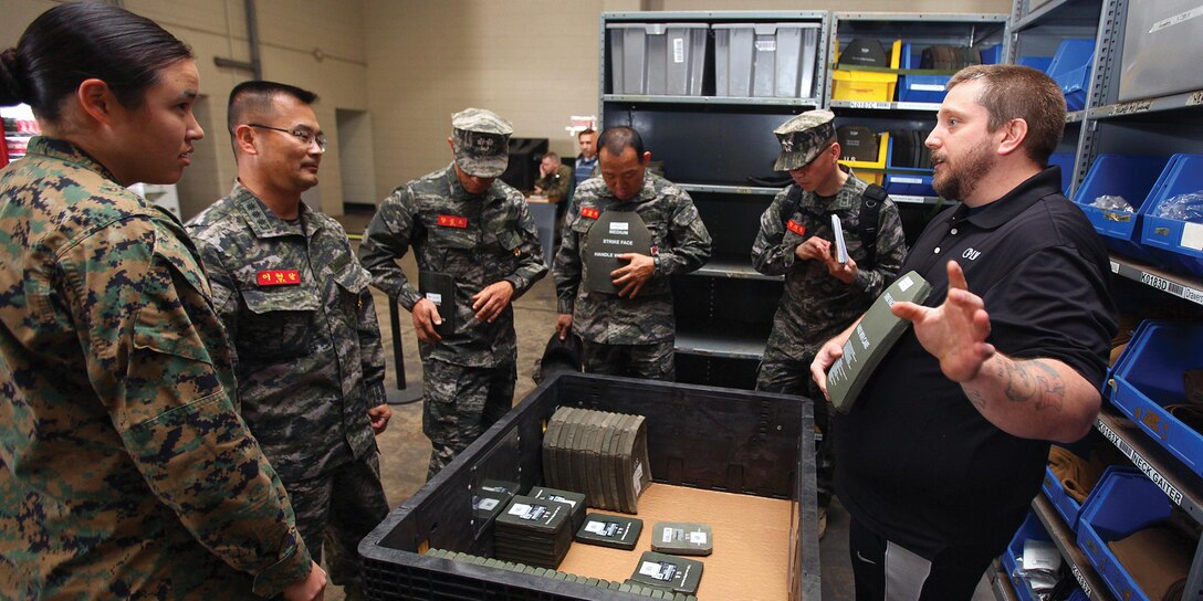 Eddie J. Dunn shows leaders of the Republic of Korea Marine Corps Amphibious Support Group small arms protective inserts during a visit from the ROK Marines to the Individual Issue Facility Nov. 19 at Camp Kinser. The ROK Marines were interested to see the system IIF uses to issue equipment to the Marines of 3rd Marine Logistics Group. Dunn is the site manager for IIF, 3rd MLG, III Marine Expeditionary Force. 