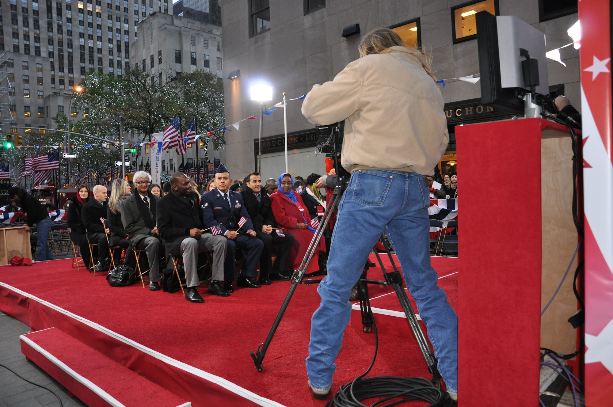 Senior Airman Jorge Contreras, 87th Logistics Readiness Squadron materiel management journeyman, sits with group of immigrants preparing to take the citizenship oath live on the "Today Show" Nov. 16, 2012, at Rockefeller Plaza in New York City. The thirty people emigrated from various countries including France, Peru and India. (U.S. Air Force photo by 2nd Lt. Alexis McGee/Released)