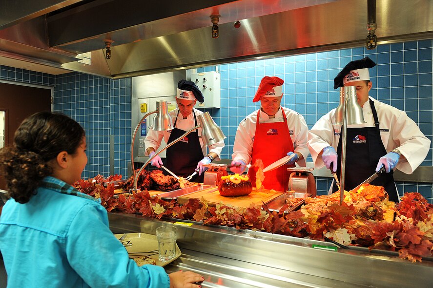 U.S. Air Force Col. John Rauch, 55th Wing commander, places ham on the plate of Gemma Duggs, daughter of retired U.S. Navy Lt. Cmdr. Edward Duggs, during Thanksgiving lunch held at the Ronald L. King Dining Facility on Offutt Air Force Base, Neb., Nov. 22. Airmen, retirees and their families member came together to celebrate Thanksgiving lunch prepared by the dining facility staff and served by base leadership. (U.S. Air Force photo by Charles Haymond/Released)