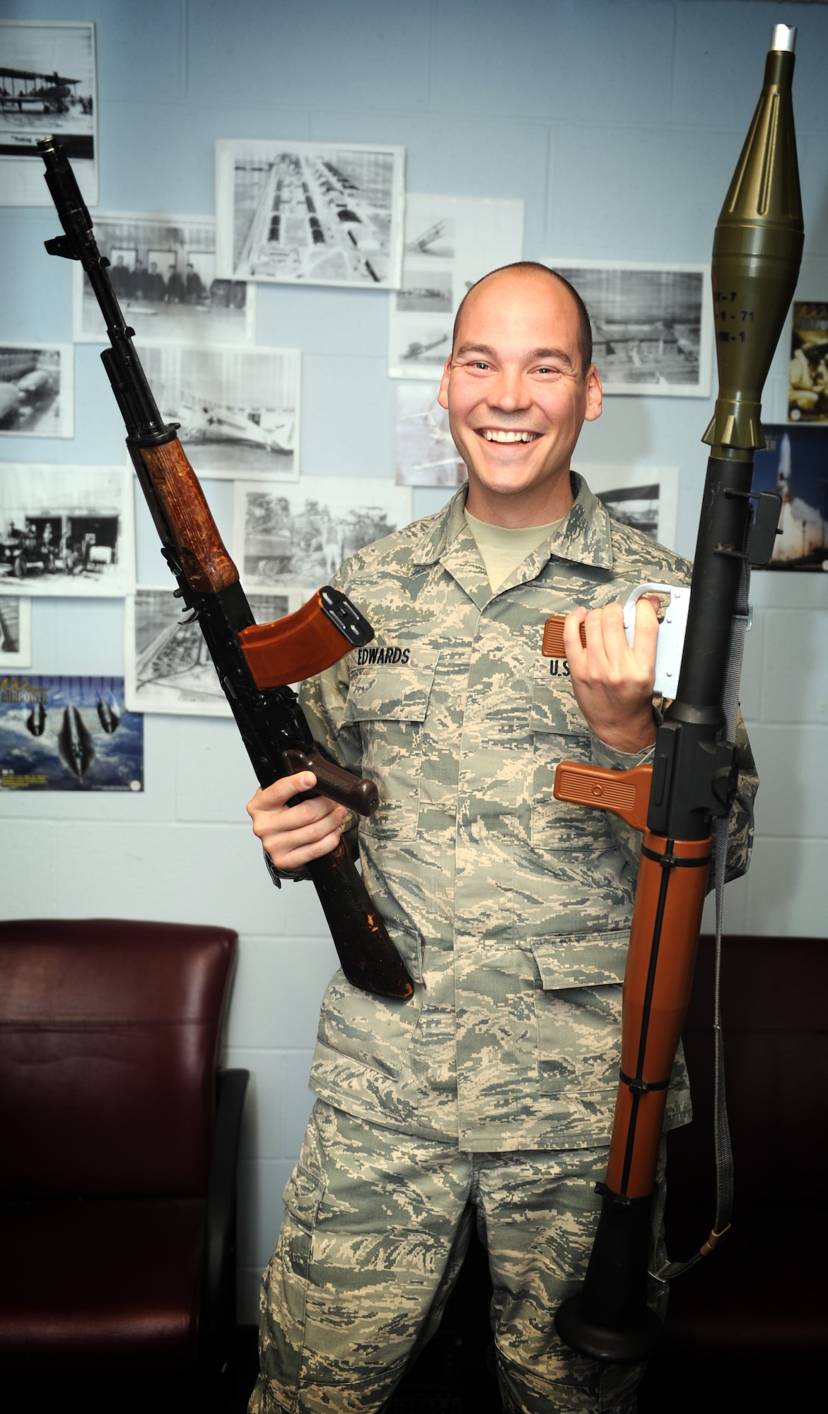 Airman 1st Class Mathew Edwards shows two prop weapons used during pre-mission briefs. The prop weapons allow deployers to get familiar with the weapons used in deployed locations. (U.S. Air Force photo/Staff Sgt. Maria Bowman)