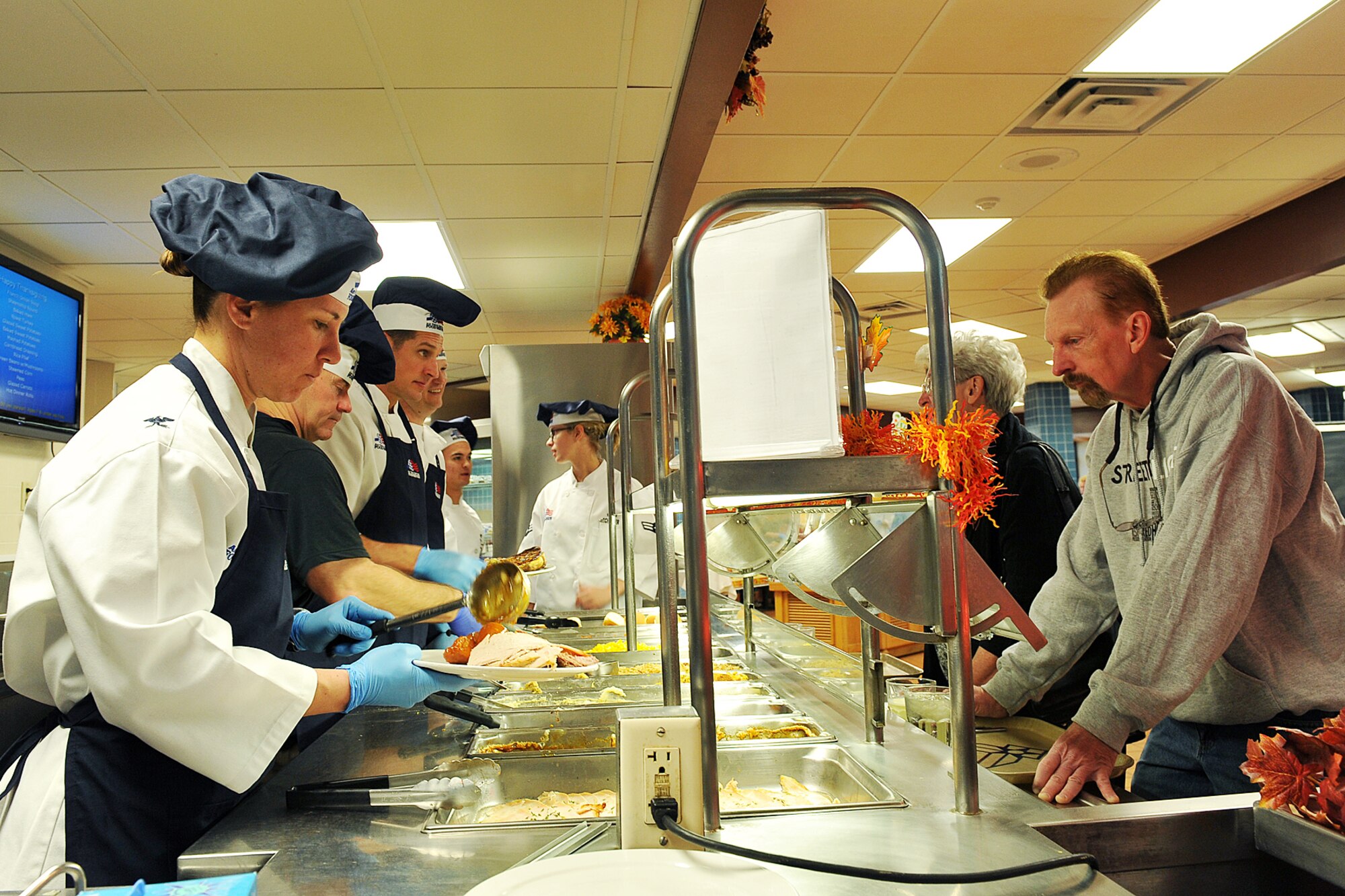 U.S. Air Force Col. Andrea Tullos, 55th Mission Support Group commander, places yams on a plate during Thanksgiving lunch at the Roland L. King Dining Facility on Offutt Air Force Base, Neb., Nov. 22. U.S. Air Force Colonels John Rauch, 55th Wing commander and Hans Palaoro, 55th Wing vice commander also spent time serving Thanksgiving lunch to Airmen. (U.S. Air Force photo by Charles Haymond/Released)