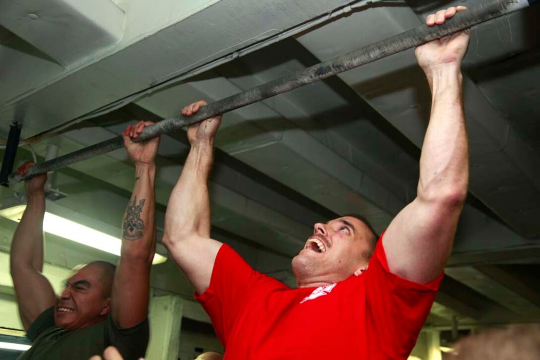 Corporal Cesar Carrillo, technical controller, Command Element, and Capt. Samuel C. Ksiazkiewicz, embarkation officer, Marine Medium Helicopter Squadron 364 (Rein.), both with 15th Marine Expeditionary unit, pull themselves up during the Campbell Cup Pull-Up Challenge in the gym of the USS Peleliu, Nov. 24. Marines and sailors of the 15th Marine Expeditionary Unit and Peleliu Amphibious Ready Group worked in teams of seven to see who could do the most pull-ups in ten minutes.  The 15th MEU is deployed as part of the Peleliu Amphibious Ready Group as a U.S. Central Command theater reserve force, providing support for maritime security operations and theater security cooperation efforts in the U.S. 5th Fleet area of responsibility. Carrillo, 24, is from Bell Gardens, Calif., and Ksiazkiewicz, 28, is from Jackson, Mich. (U.S. Marine Corps photo by Cpl. John Robbart III/Released)