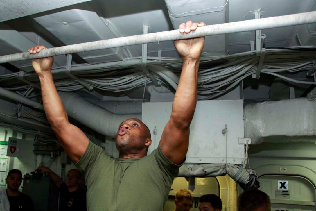 Sergeant Maj. John W. Scott, sergeant major, 15th Marine Expeditionary Unit, pulls himself up during the Campbell Cup Pull-Up Challenge in the gym of the USS Peleliu, Nov. 24. Marines and sailors of the 15th Marine Expeditionary Unit and Peleliu Amphibious Ready Group worked in teams of seven to see who could do the most pull-ups in ten minutes.  The 15th MEU is deployed as part of the Peleliu Amphibious Ready Group as a U.S. Central Command theater reserve force, providing support for maritime security operations and theater security cooperation efforts in the U.S. 5th Fleet area of responsibility. (U.S. Marine Corps photo by Cpl. John Robbart III/Released)