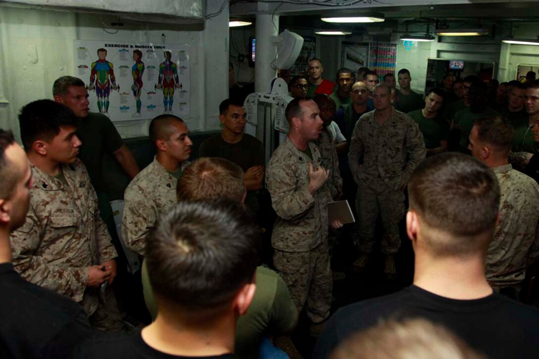 Petty Officer 1st Class Edward S. Debaun, religious program specialist, Command Element, 15th Marine Expeditionary Unit, explains the rules of the  Campbell Cup Pull-Up Challenge in the gym of the USS Peleliu, Nov. 24. Marines and sailors of the 15th Marine Expeditionary Unit and Peleliu Amphibious Ready Group worked in teams of seven to see who could do the most pull-ups in ten minutes.  The 15th MEU is deployed as part of the Peleliu Amphibious Ready Group as a U.S. Central Command theater reserve force, providing support for maritime security operations and theater security cooperation efforts in the U.S. 5th Fleet area of responsibility. Debaun, 34, is from Copperopolis, Calif. (U.S. Marine Corps photo by Cpl. John Robbart III/Released)