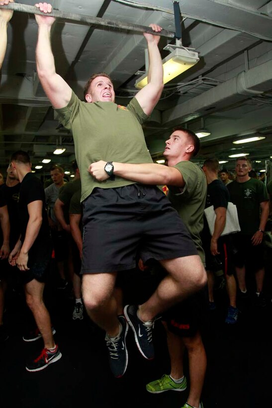 First Lt. James P. Rooney, platoon commander, Weapons Platoon, pulls himself up while 1st Lt. Murphy A. Bright, platoon commander, 3rd Platoon, both with Kilo Company, Battalion Landing Team 3/5, 15th Marine Expeditionary Unit, prevents him from swaying back and forth during the Campbell Cup Pull-Up Challenge in the gym of the USS Peleliu, Nov. 24. Marines and sailors of the 15th Marine Expeditionary Unit and Peleliu Amphibious Ready Group worked in teams of seven to see who could do the most pull-ups in ten minutes.  The 15th MEU is deployed as part of the Peleliu Amphibious Ready Group as a U.S. Central Command theater reserve force, providing support for maritime security operations and theater security cooperation efforts in the U.S. 5th Fleet area of responsibility. Rooney, 25, is form Long Island, N.Y., and Bright, 24, is from New York. (U.S. Marine Corps photo by Cpl. John Robbart III/Released)