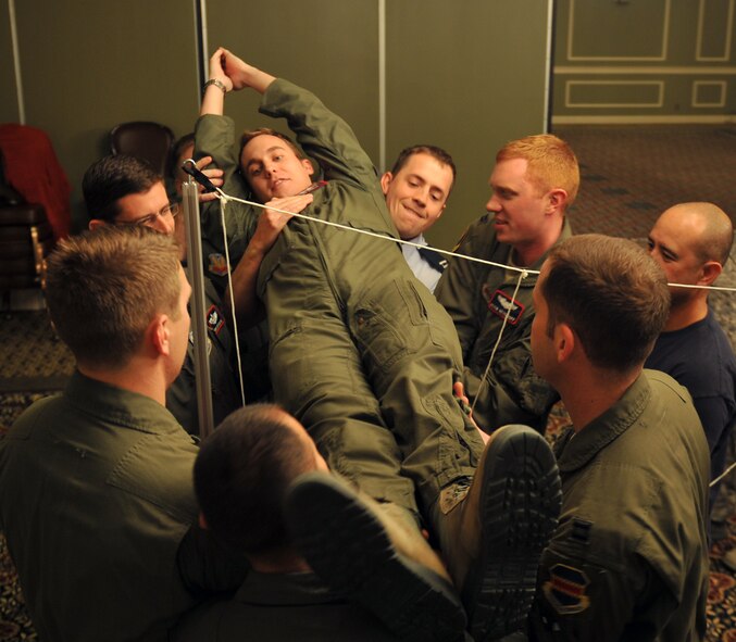 Members of the 38th Reconnaissance Squadron work together in a team building obstacle inside the Patriot Club on Offutt Air Force Base, Neb., Nov. 26. The exercise was just one of the scheduled events during the annual Wingman Day, where Airmen got to participate in team building activities and sports. (U.S. Air Force photo by Jeff W. Gates/Released)