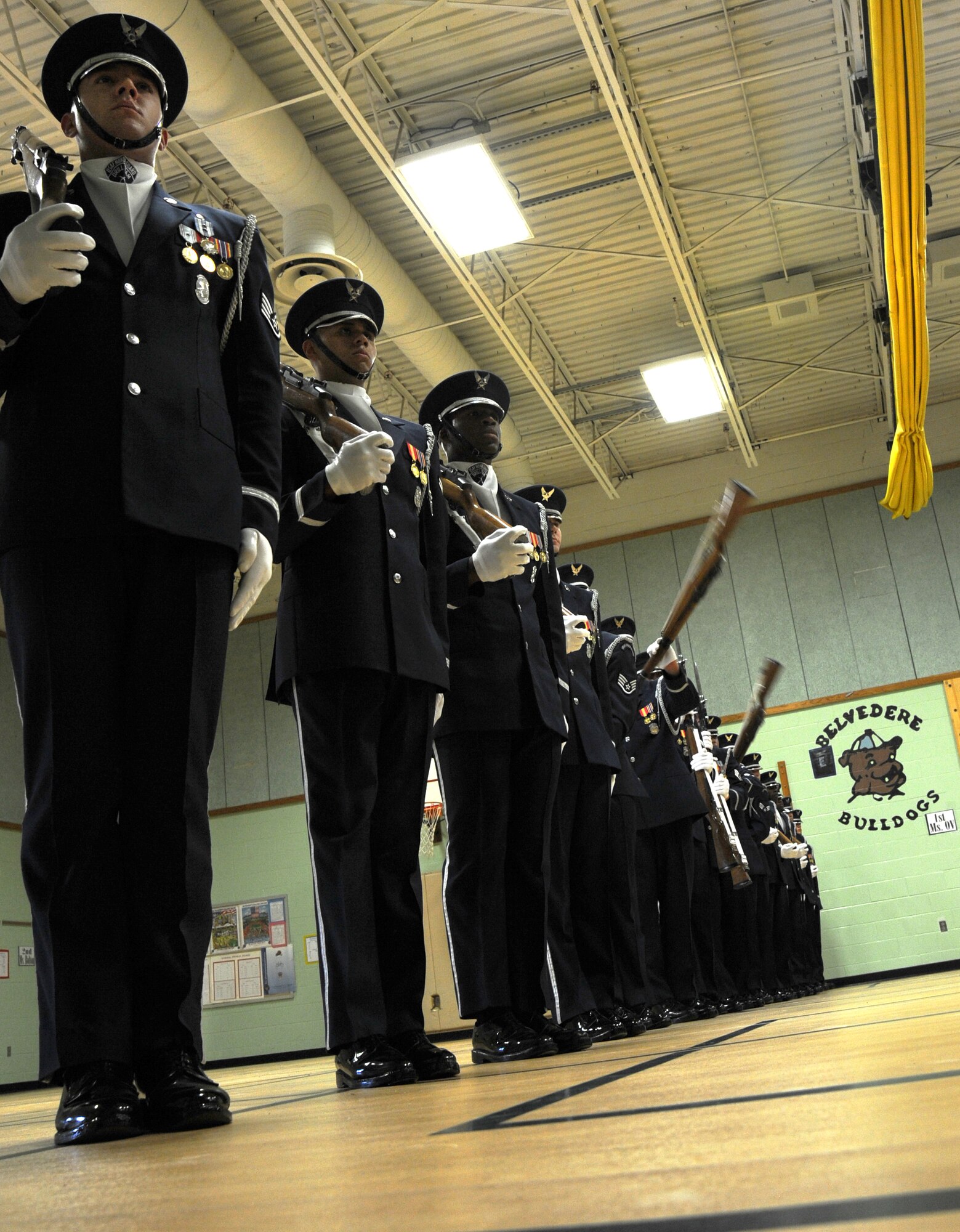 Members of the U.S. Air Force Honor Guard Drill Team sequentially spin their M-1 rifles during a performance at Belvedere Elementary School in Falls Church, Va., Nov. 26, 2012.   After the performance, Drill Team members and students planted trees at a plot of land near the school which the students are transforming into Belvedere Park.  (U.S. Air Force photo/Staff Sgt. Torey Griffith)