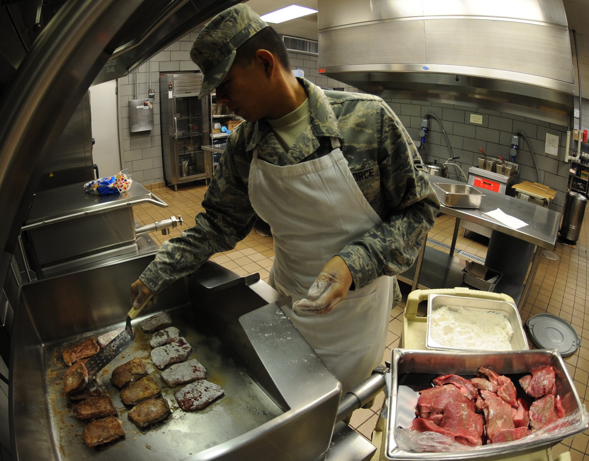 Airman 1st Class Marco Tordera, 509th Force Support Squadron food services technician, prepares Swiss Steaks on a Tilt Grill at the Ozark Inn Dining Facility Nov. 2 at Whiteman Air Force Base, Mo. The Ozark Inn provides nutrition facts for all meals served. (U.S. Air Force photo/Airman 1st Class Bryan Crane) (Released)