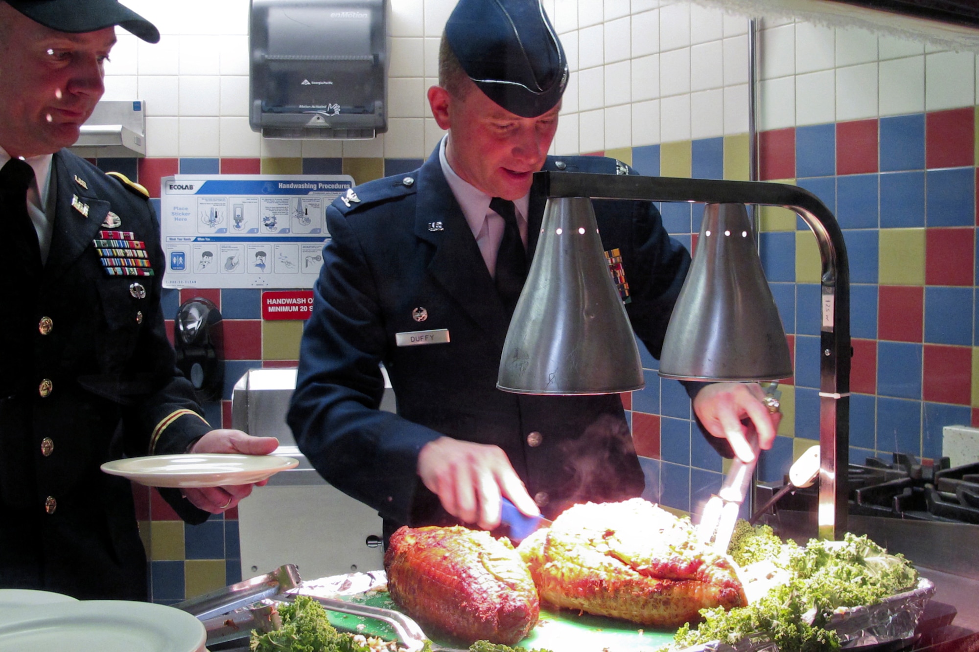 JOINT BASE ELMENDORF-RICHARDSON, Alaska -- Army Col. Thomas Roth, 2nd Engineer Brigade commander, looks on as Air Force Col. Brian Duffy, 673rd Air Base Wing commander, carves turkey during a Thanksgiving luncheon held at the Wilderness Inn, November 21, 2012.  (U.S. Air Force photo/Percy G. Jones)