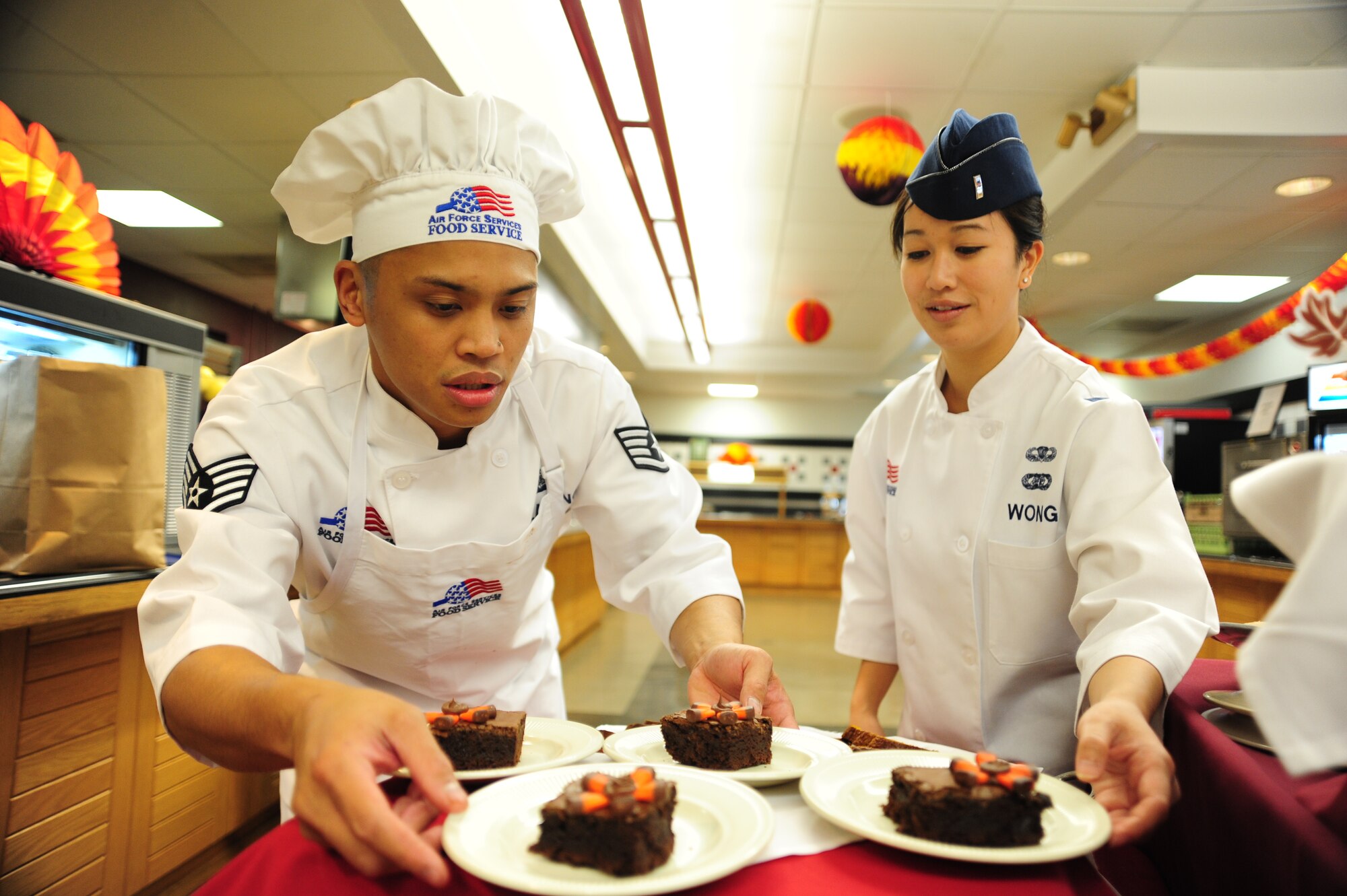Staff Sgt. Jerry Calalang, and 1st Lt. Diana Wong, 509th Force Support Squadron, position desserts for the Thanksgiving Day Meal at the Ozark Inn Dining Facility, Whiteman Air Force Base, Mo., Nov. 22. Each year the dining facility hosts a Thanksgiving Day meal for Airmen and their families. This event boosts morale for Airmen that are working through the holidays and can’t make it home to their families. (U.S. Air Force photo/Senior Airman Nick Wilson) (Released)
