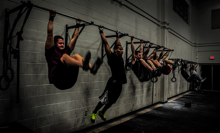 Service members and dependents perform kipping pull-ups during a CrossFit class Nov. 19, 2012, at the Joint Base Charleston – Air Base Fitness Center. The group combined weightlifting, calisthenics and running during an hour-long workout session. The CrossFit classes are open to all military members, DOD employees and dependents. (U.S. Air Force photo/ Senior Airman Dennis Sloan)