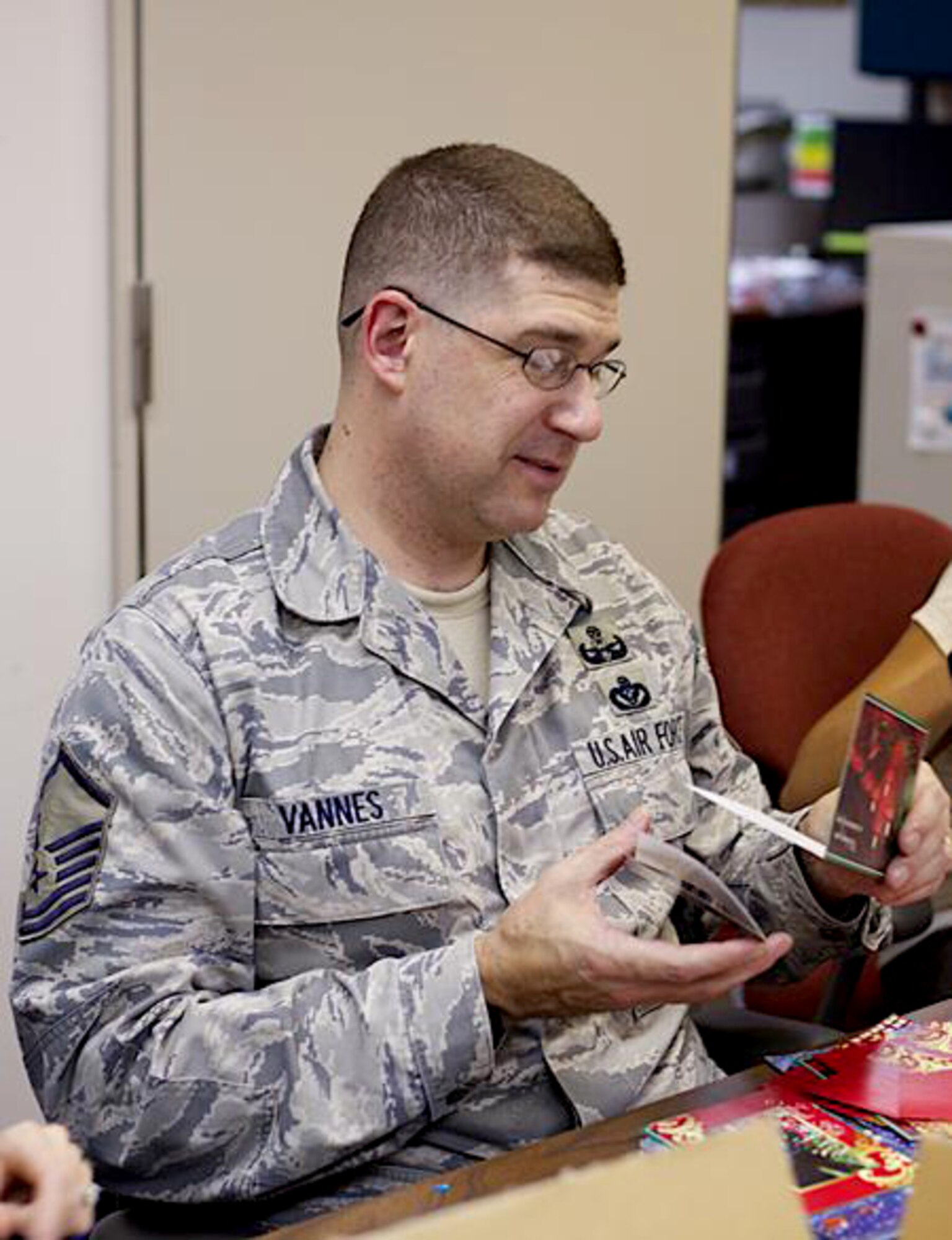U.S. Air Force Master Sgt. Garet Vannes, American Red Cross Holiday Mail for Heroes Campaign volunteer, glances at a card while sorting through holiday letters and cards for the Holiday Mail For Heroes Campaign at Misawa Air Base, Japan, Nov. 27, 2012. Over the last five years, the campaign has collected more than four million cards filled with messages of gratitude, encouragement and holiday greetings from the American public for members of the U.S. Armed Forces. (Courtesy photo)