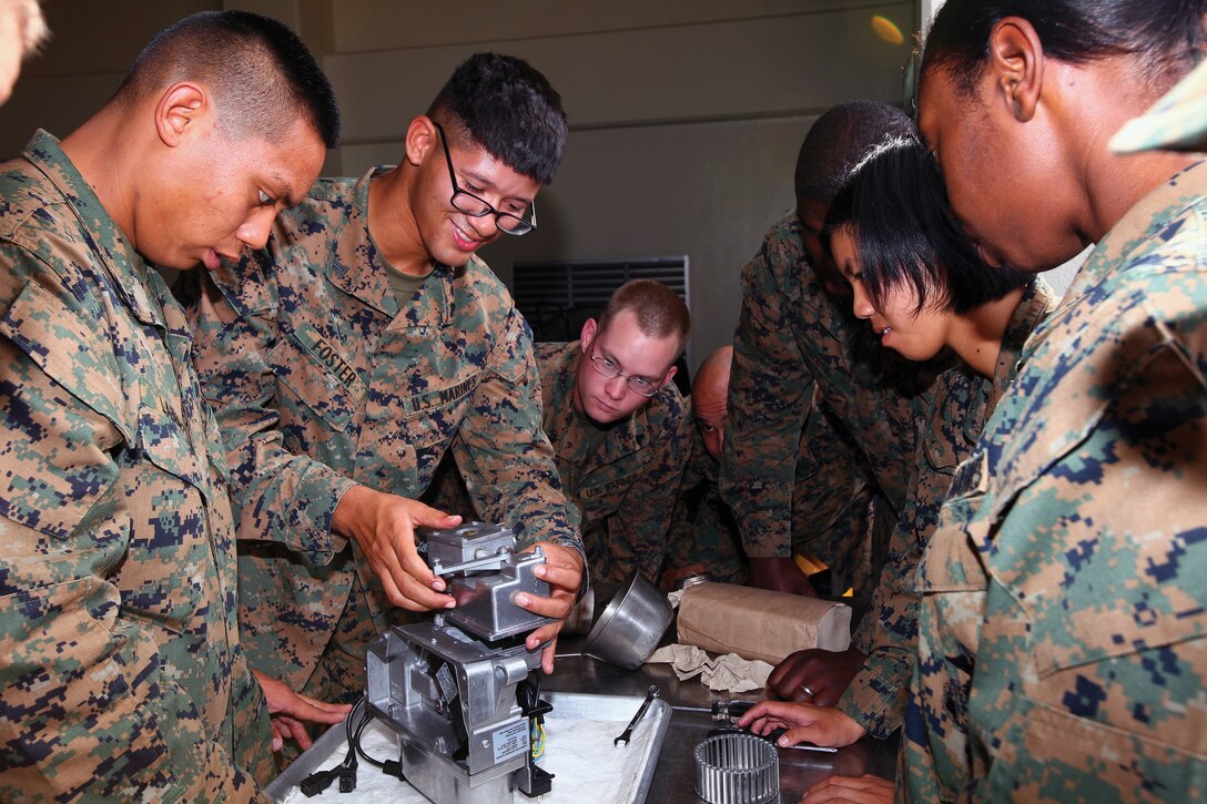 Marines rebuild a Babington airtronic burner during field mess training at Camp Kinser Nov. 16. The burner is the main heat source for the tray ration heating system, the main system Marines use to cook unitized group rations in field environments. The Marines are with units throughout III Marine Expeditionary Force.