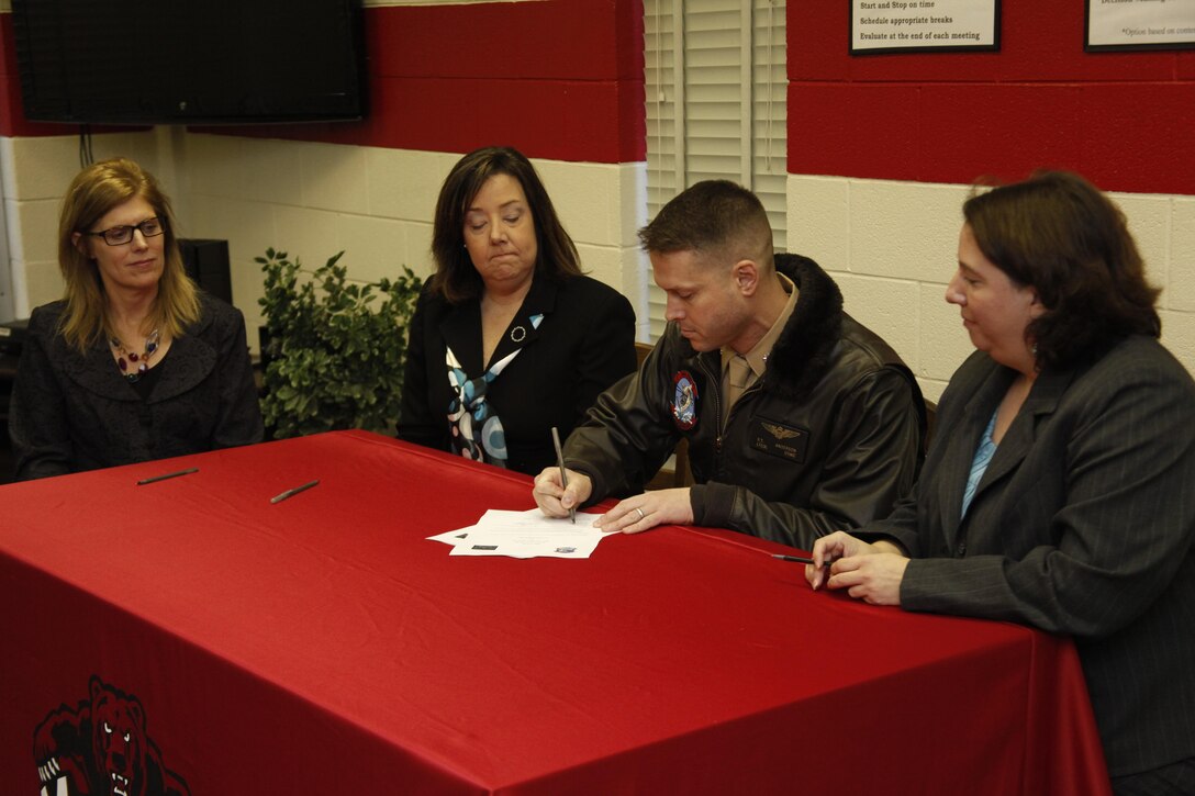 Lt. Col. Richard T. Anderson Marine Heavy Helicopter Squadron 366’s commanding officer, signs an adoption contract with leadership from H.J. MacDonald Middle School at the school Nov. 19. The squadron plans to support the school by providing students with mentors and tutors who will help with their studies.
