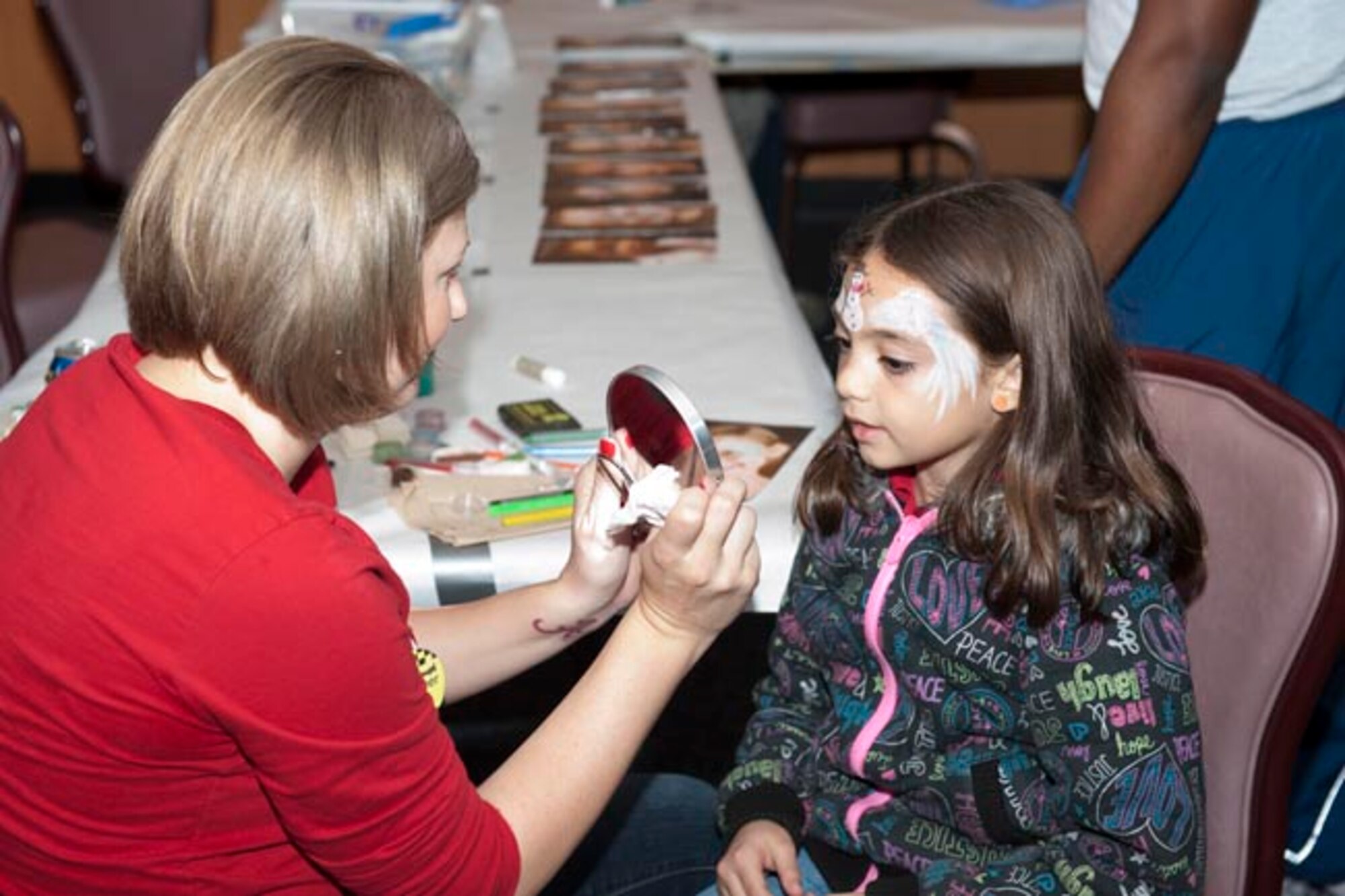 Juliette Tufano looks in the mirror after getting her face painted by Staff Sgt. Sabrina Robertson, 325th Aeromedical-Dental Squadron NCO in charge of the clinical element, during the Hearts Apart Holiday party Nov. 29 at Horizons Sports Lounge. Nearly 50 dependents attended the party which offered multiple activity stations such as arts and crafts, face painting and the presentation of gifts from Santa Claus. Hearts Apart is an event held quarterly by Airmen and Family Readiness for the dependents of deployed service members. The program’s main goal is to show appreciation to spouses and children by keeping them involved with the base community. (U.S. Air Force photo by Chris Cokeing)