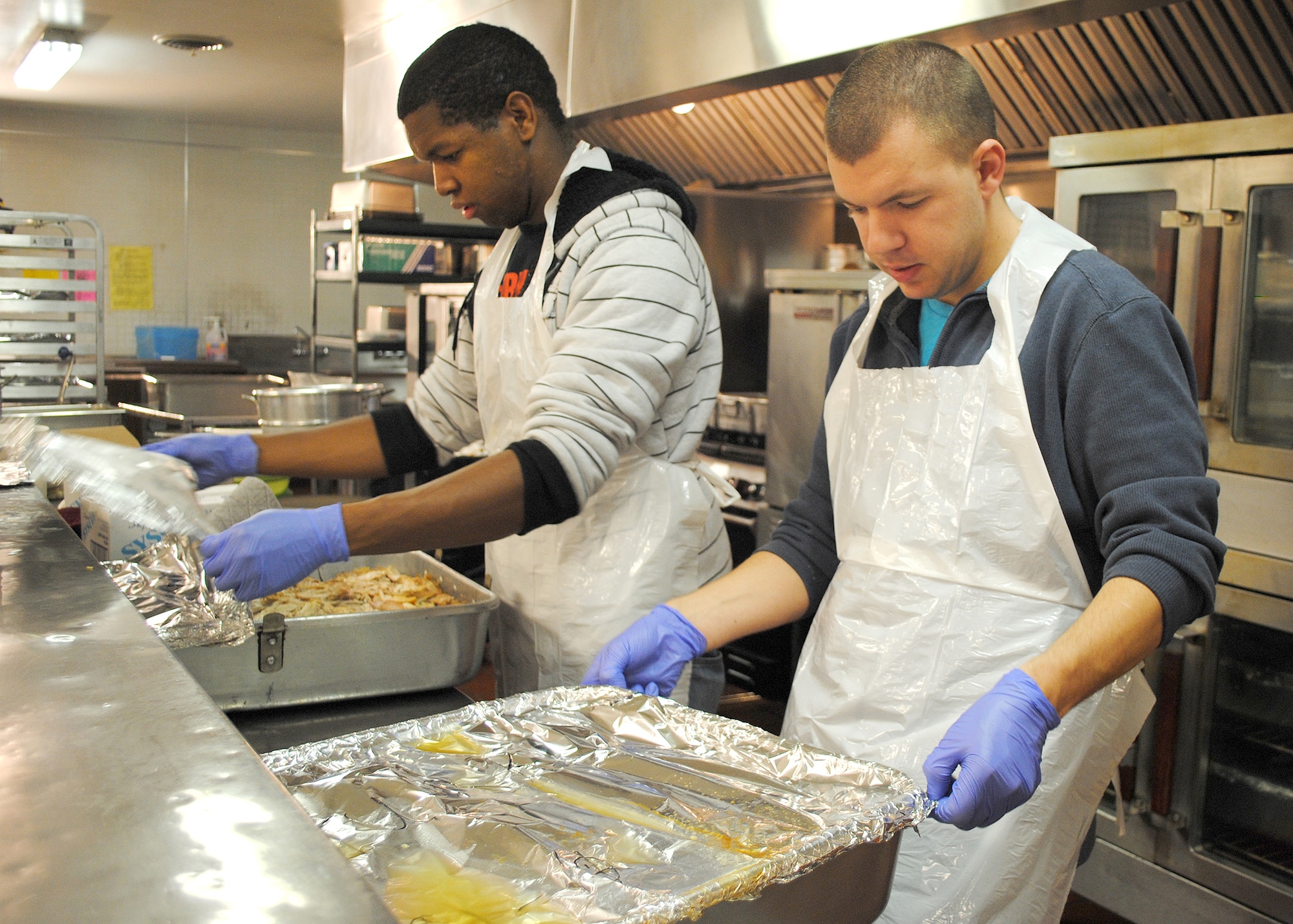 Greene, left, and Ensminger reheat turkey before packing it for delivery. Ensminger was the alternate point of contact for Thanksgiving Meals on Wheels at the Great Falls Community Food Bank and was crucial to making the volunteer project a success. (U.S. Air Force photo/Airman 1st Class Katrina Heikkinen) 