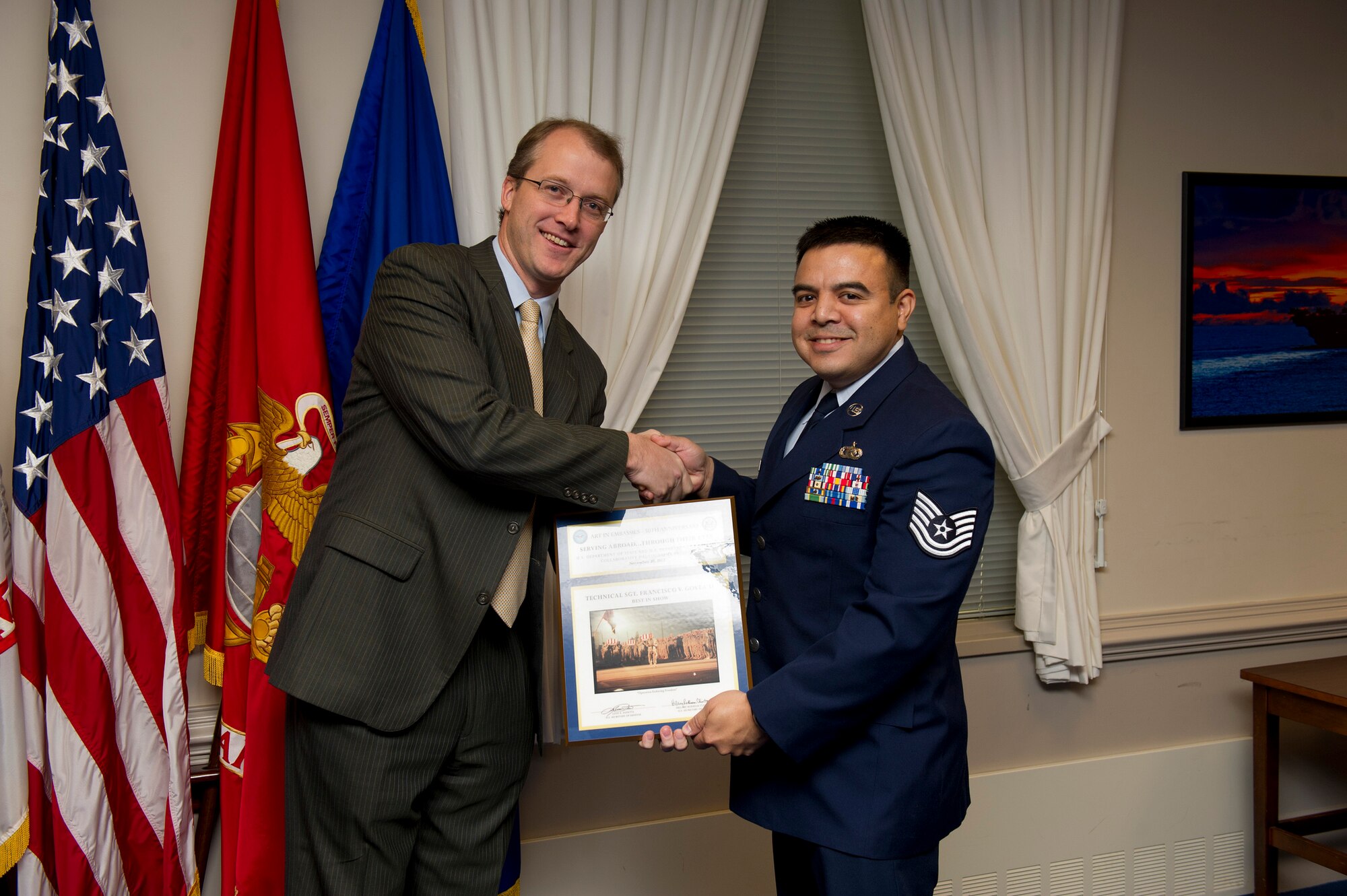 Pentagon Press Secretary George E. Little, left, hands over the "Best in Show" photography award to Tech. Sgt. Francisco V. Govea II, during the Art in Embassies best in show awards ceremony at the Pentagon, Nov 30, 2012. Govea is stationed at March Air Force Base, Calif.
