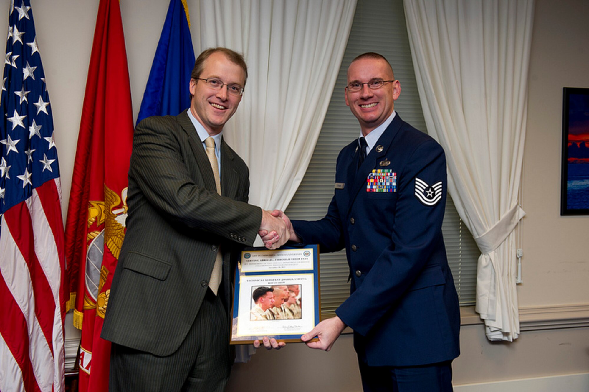 Pentagon Press Secretary George E. Little, left, smiles as he hands over the "Best in Show" photography award to Tech. Sgt. Joshua Strang, during the Art in Embassies best in show awards ceremony at the Pentagon, Nov 30, 2012. Strang is an instructor at the Defense Information School at Fort Meade, Md. 