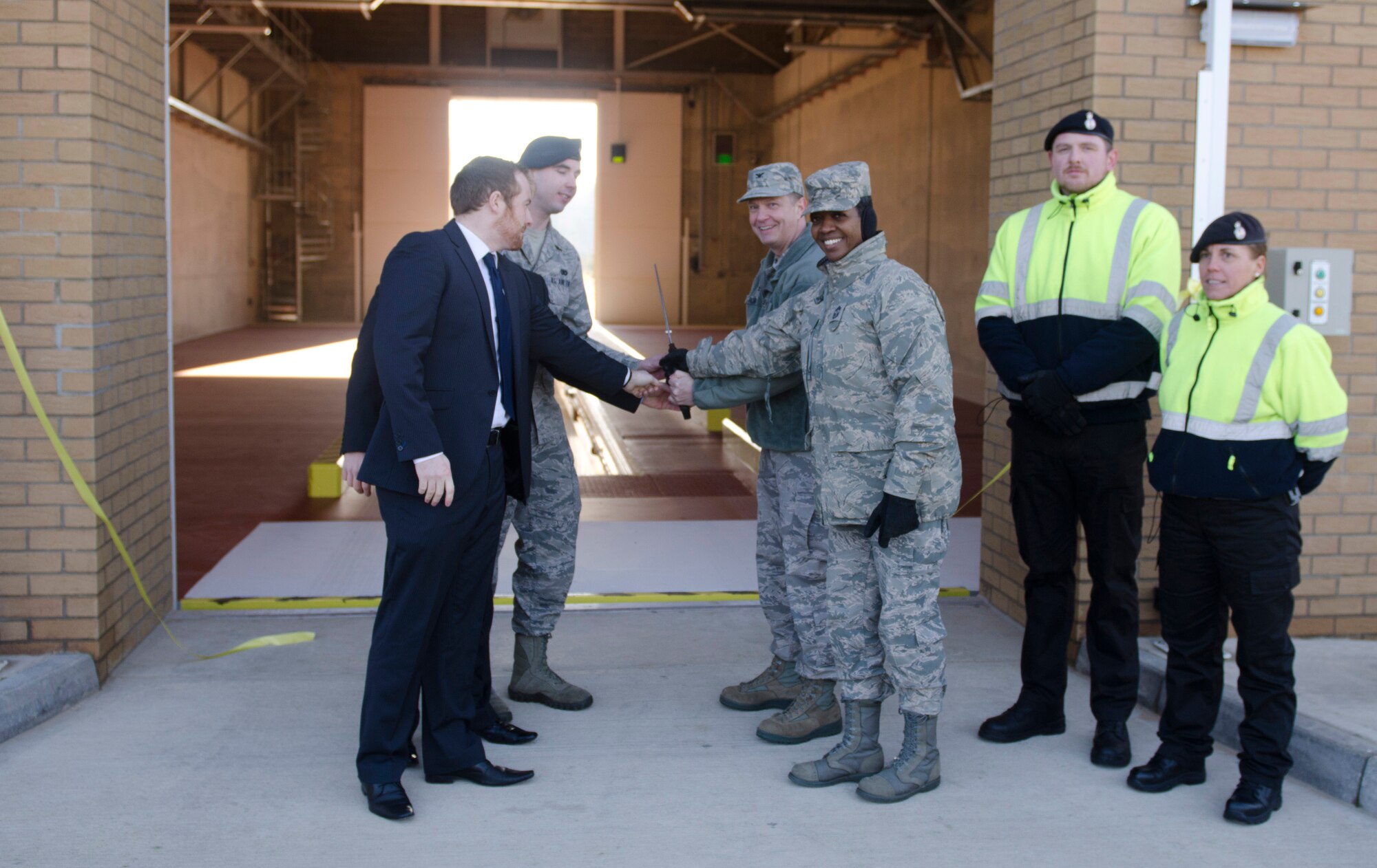 ROYAL AIR FORCE LAKENHEATH, England - Col. Kyle Robinson (center), 48th Fighter Wing commander, Chief Master Sgt. SaRita Lathan (center right), 48th FW command chief, and other Team Lakenheath members cut a ribbon during a ceremony for the Large Vehicle Inspection Site Nov. 30, 2012. The LVIS, a new gate specifically for large vehicles entering RAF Lakenheath will be open Monday through Friday from 6 a.m. to 6 p.m. beginning Dec. 3. (U.S. Air Force photo by Staff Sgt. Stephen Linch)