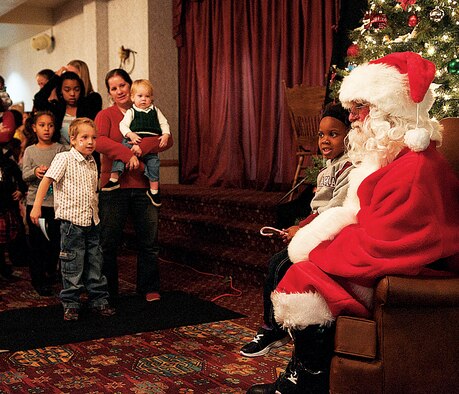 Saraya Henderson, daughter of Staff Sgt. Ashley Henderson, 90th Security Forces Squadron, poses for a photograph with Santa Claus while other children wait their turn to talk to Santa and get their photo taken with him in the Trail’s End Club Nov. 24. Guests had breakfast and watched a magic show prior to the arrival of Santa Claus. (U.S. Air Force photo by Airman 1st Class Jason Wiese)