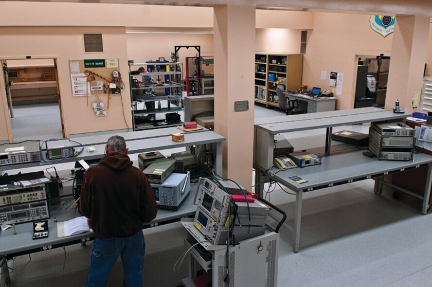 Brian Brothers works in the main laboratory of the Precision Measurement Equipment Laboratory on F. E. Warren Air Force Base, Wyo., Nov. 14. In the background, Tom Patton works in the torque wench section of the physical/dimensional area of the lab. (U.S. Air Force photo by R.J. Oriez)